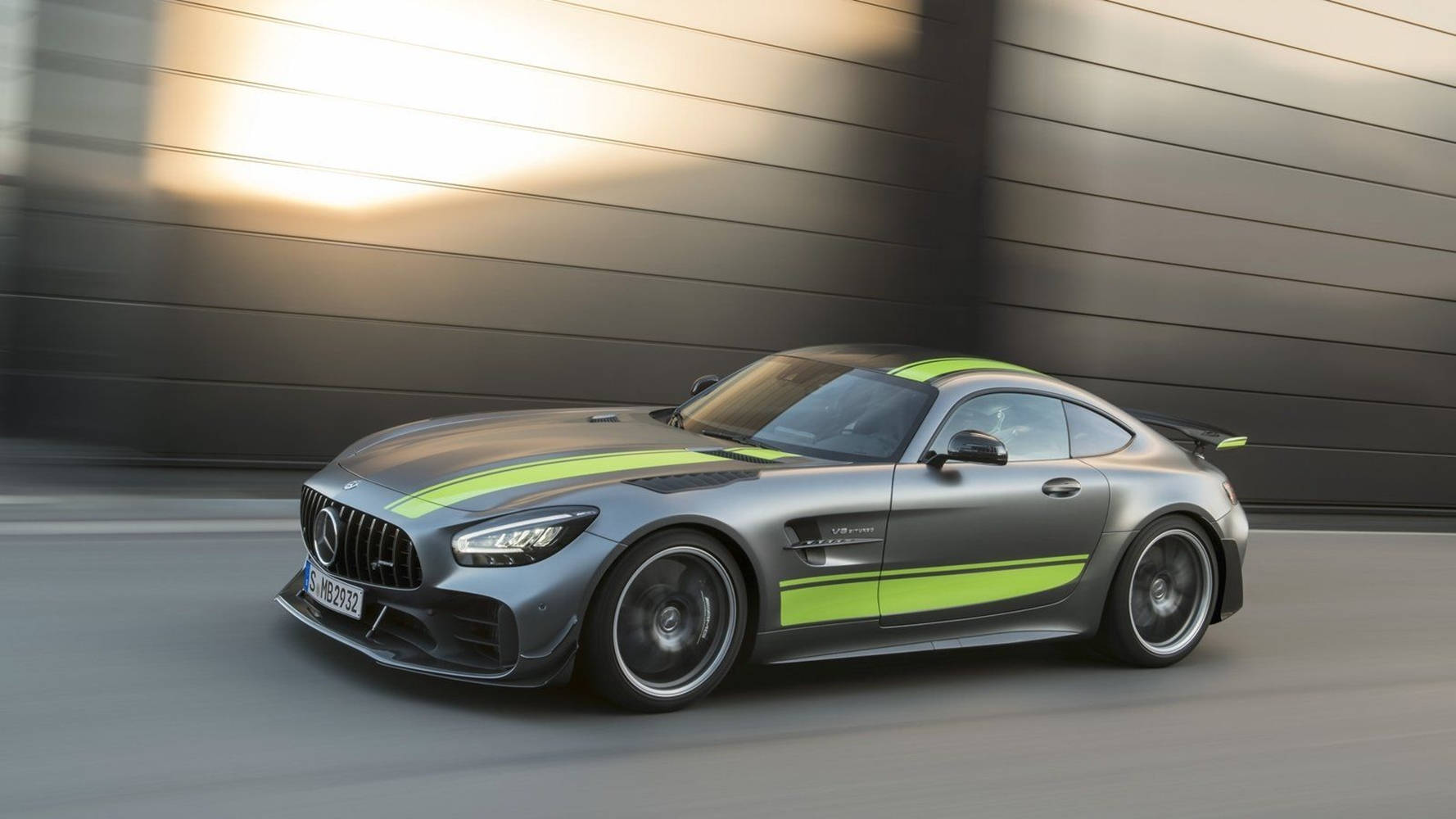 Gtr 桌布 壁紙 — 一輛時尚的銀色 Mercedes-AMG GT R 帶有螢光綠色條紋，以動態模糊效果駛過現代金屬牆。