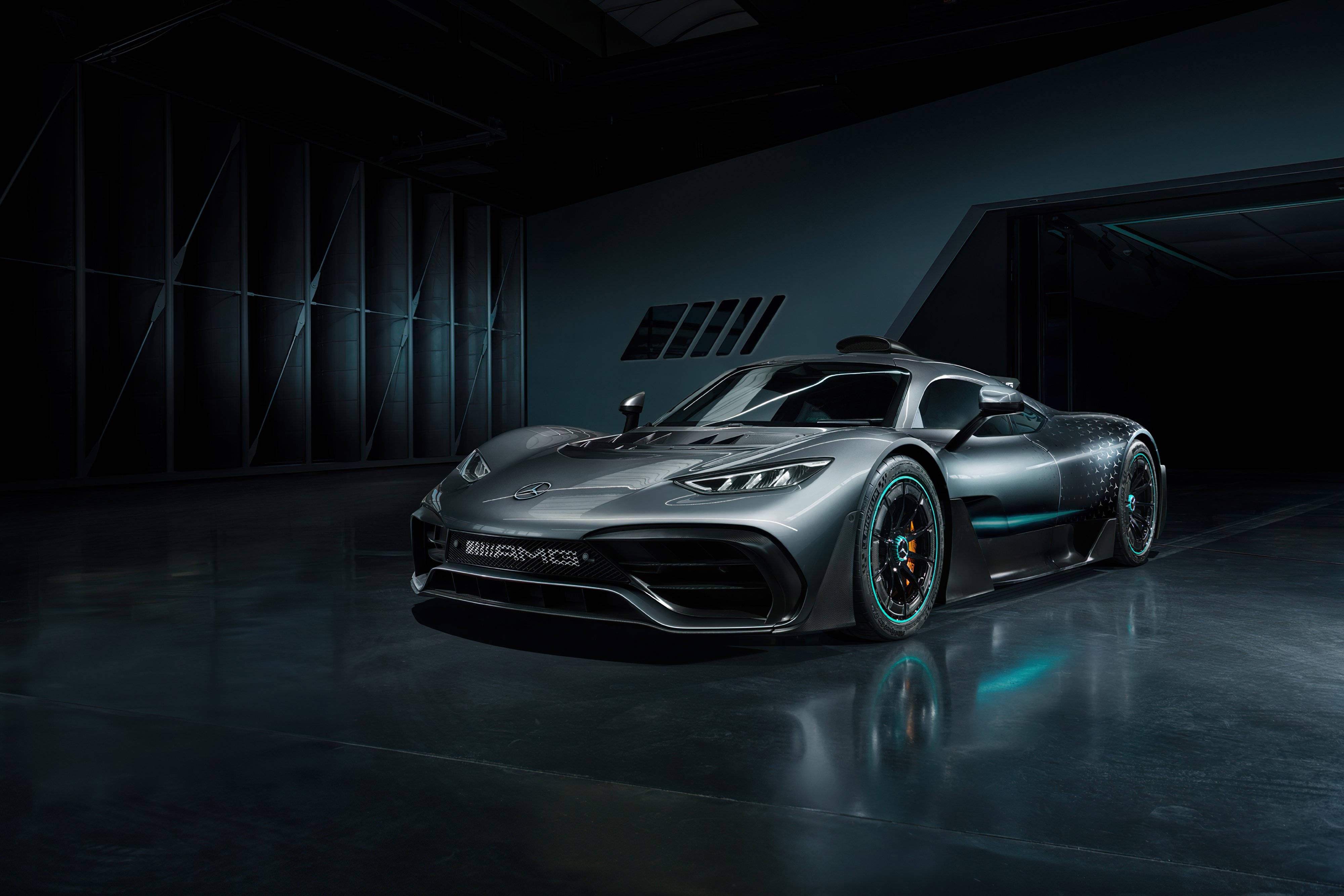 Amg 桌布 壁紙 — 一輛時尚的銀色 Mercedes-AMG One 超跑在昏暗的工業車庫中，在戲劇性的燈光下閃閃發光。