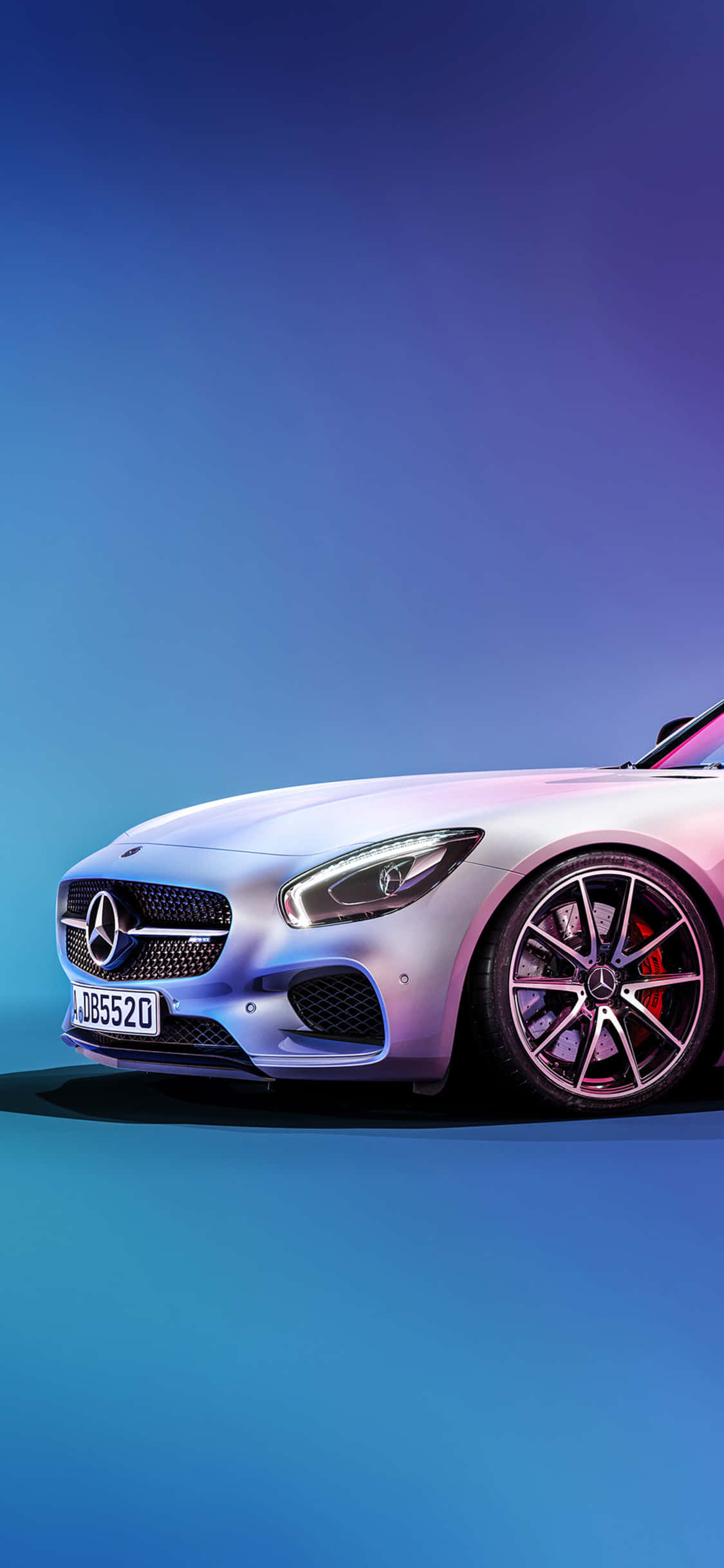 iPhone X Amg Gt-r 桌布 壁紙 — 一輛時尚的銀色 Mercedes-AMG GT 跑車在充滿活力的藍色和紫色工作室燈光下閃耀。