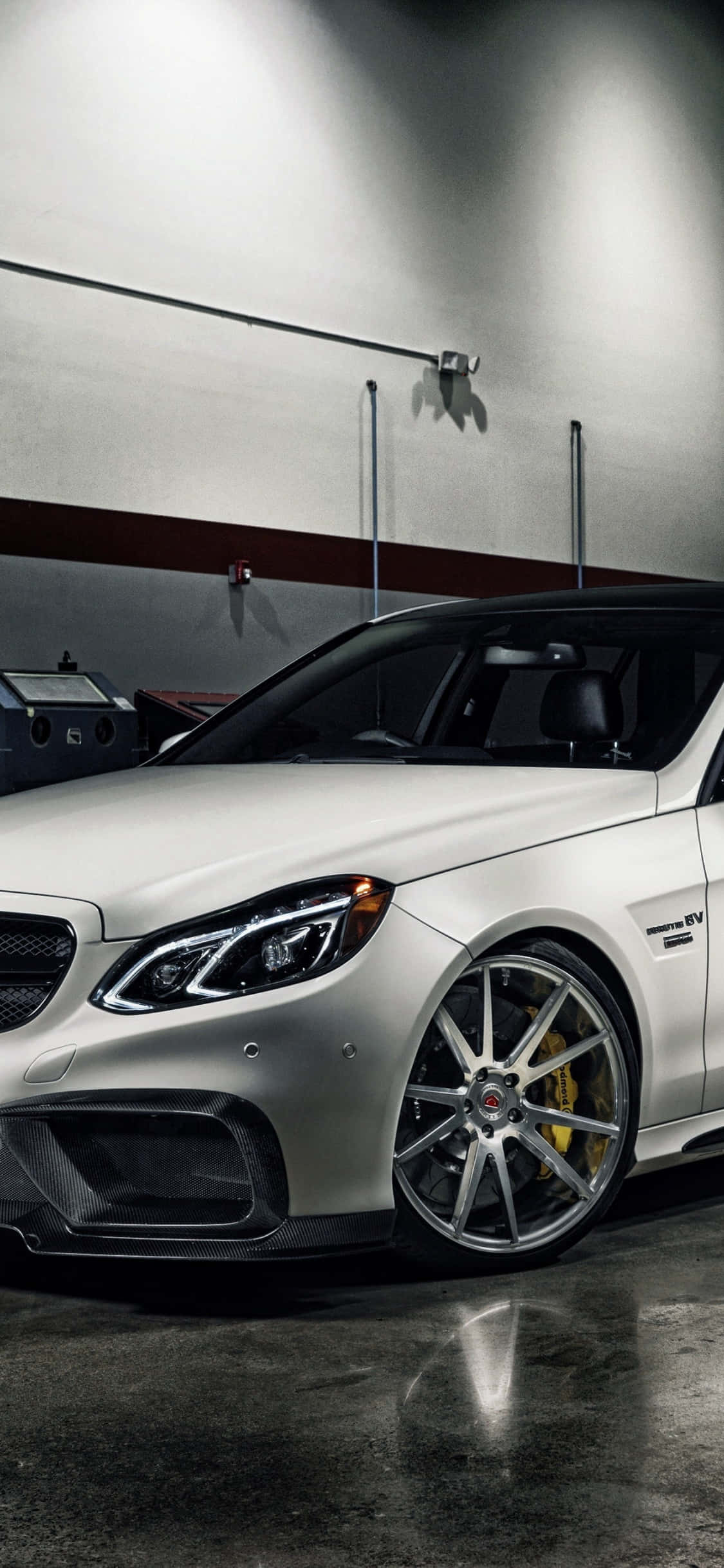 Mercedes 桌布 壁紙 — 一輛時尚的銀色 Mercedes-AMG 跑車配備金色制動卡鉗，停在光線昏暗、地板拋光混凝土的車庫中。