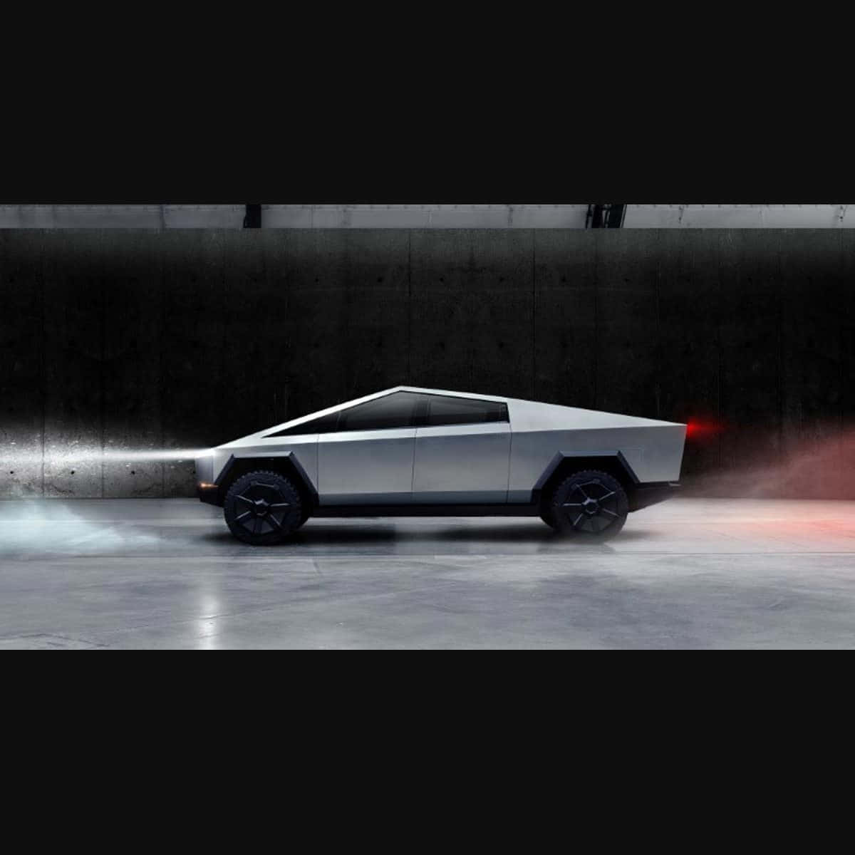 Tesla Cybertruck 桌布 壁紙 — 一輛時尚的銀色 Tesla Cybertruck 在黑暗的混凝土隧道中疾馳，車頭燈閃爍，紅色尾燈明亮。