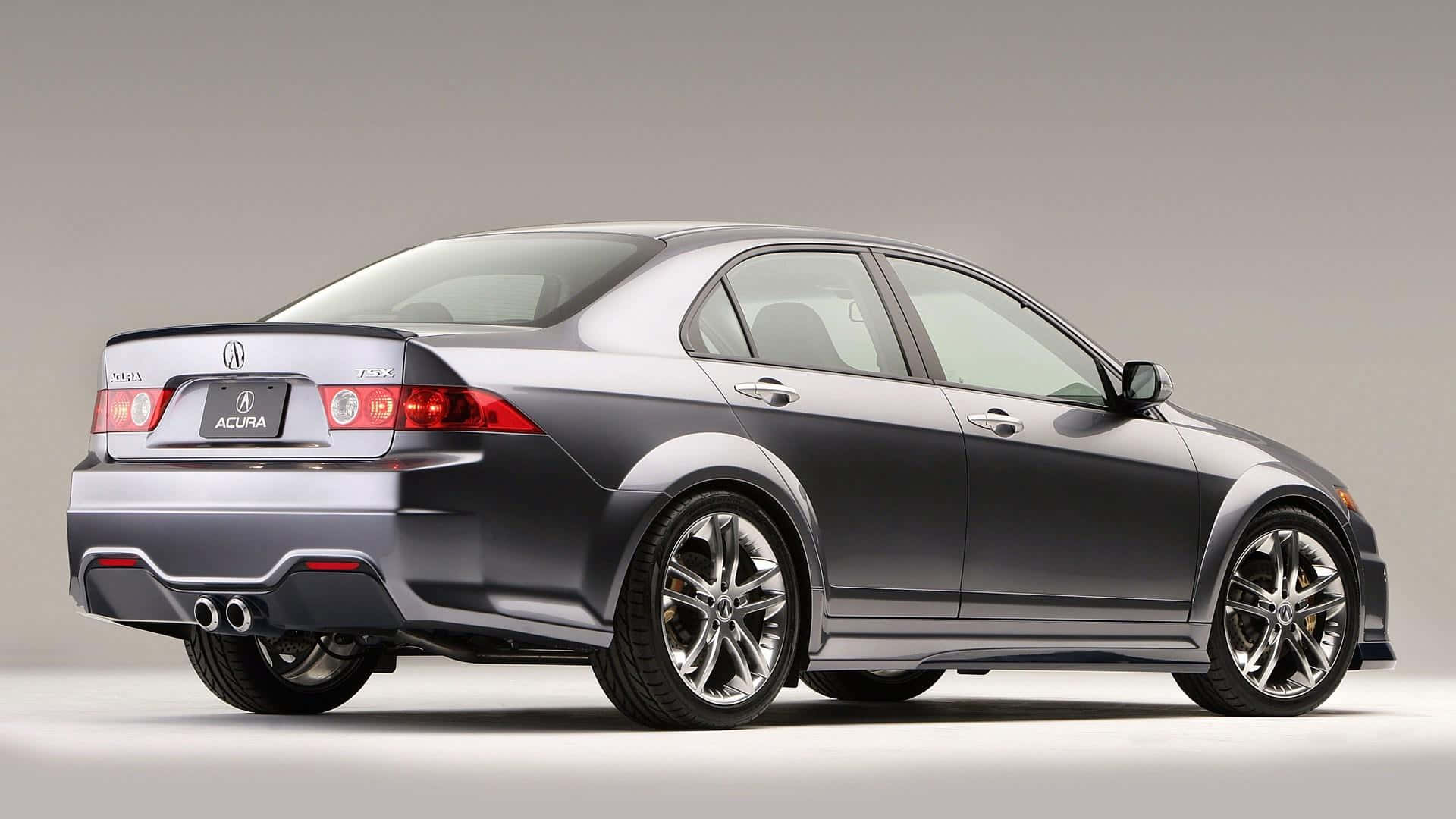 Acura Tsx 桌布 壁紙 — 一輛時尚的銀色Acura TSX轎車，在工作室燈光下展示，配有紅色尾燈和雙排氣管。