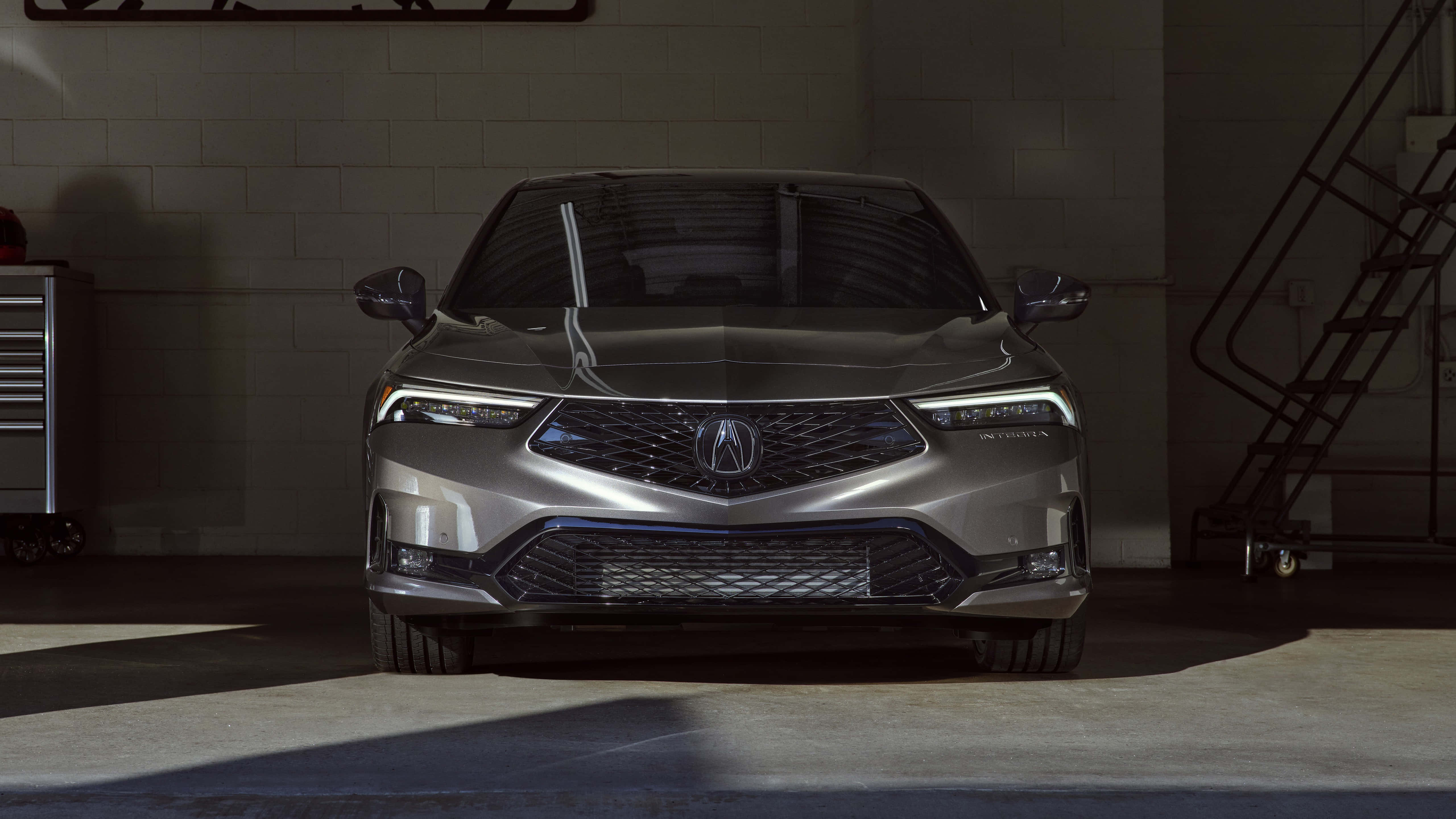 Acura Integra 桌布 壁紙 — 一輛時尚的銀色Acura轎車位於光線昏暗的車庫中央，車庫有混凝土牆和金屬樓梯投下陰影。