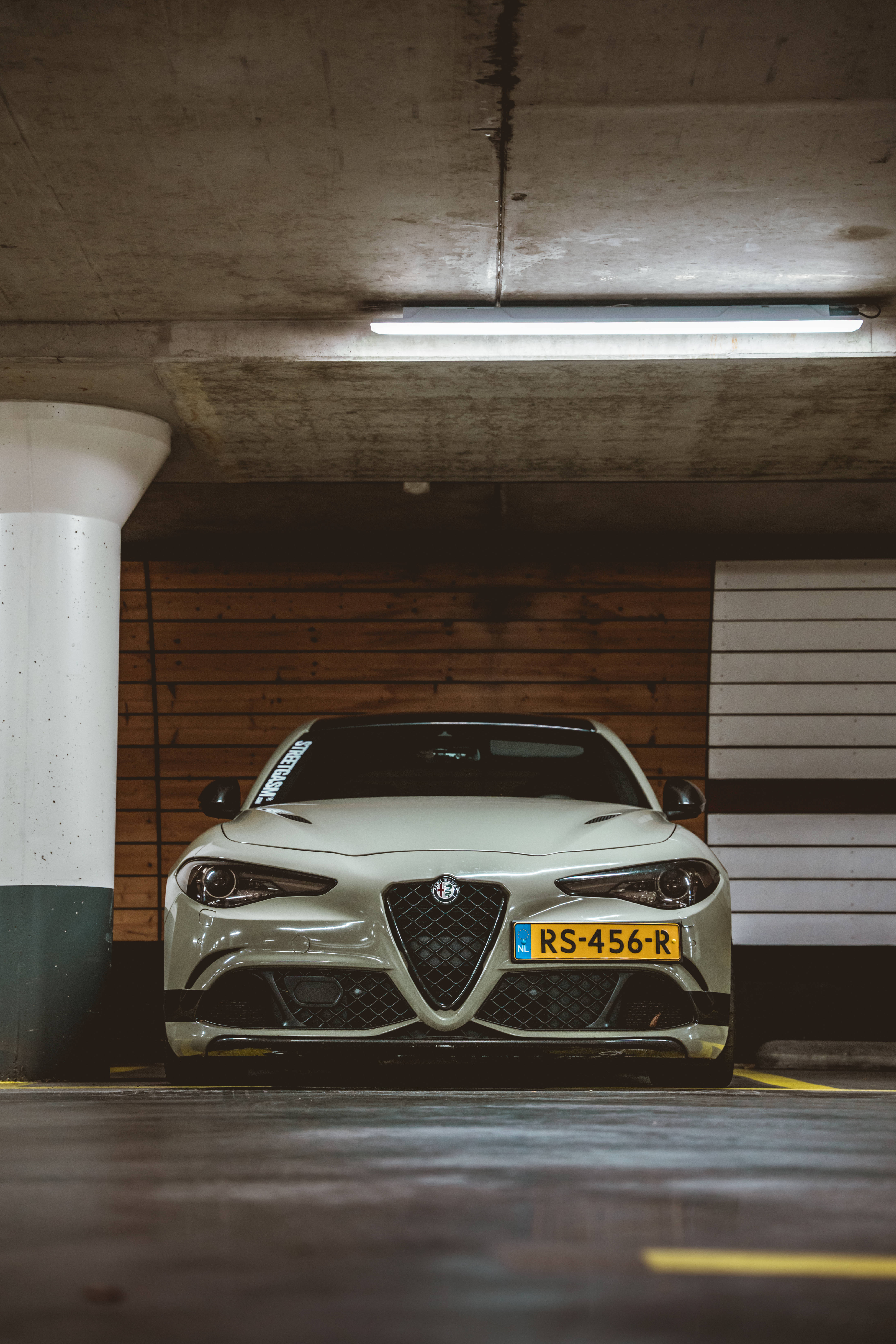 Alfa Romeo 桌布 壁紙 — 一輛時尚的銀色Alfa Romeo跑車停在混凝土車庫燈光下，配有木質牆板。