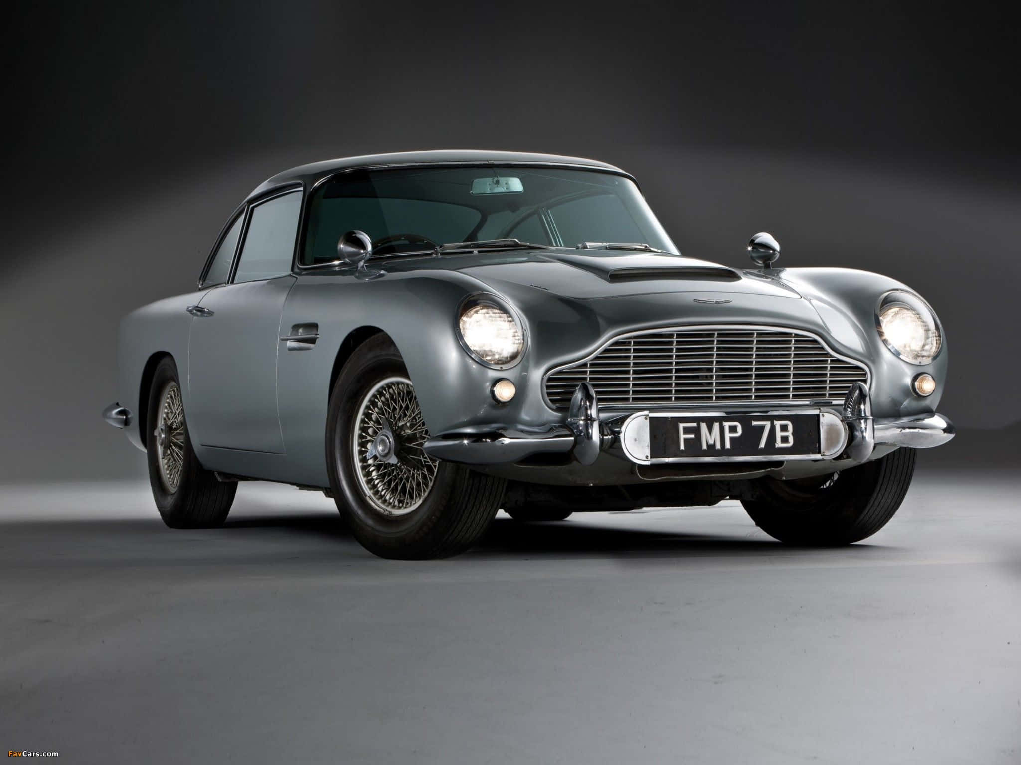 Aston Martin Db5 桌布 壁紙 — 一輛時尚的銀色Aston Martin DB5在攝影棚燈光下閃耀，配備鍍鉻裝飾和經典鋼絲輪圈。
