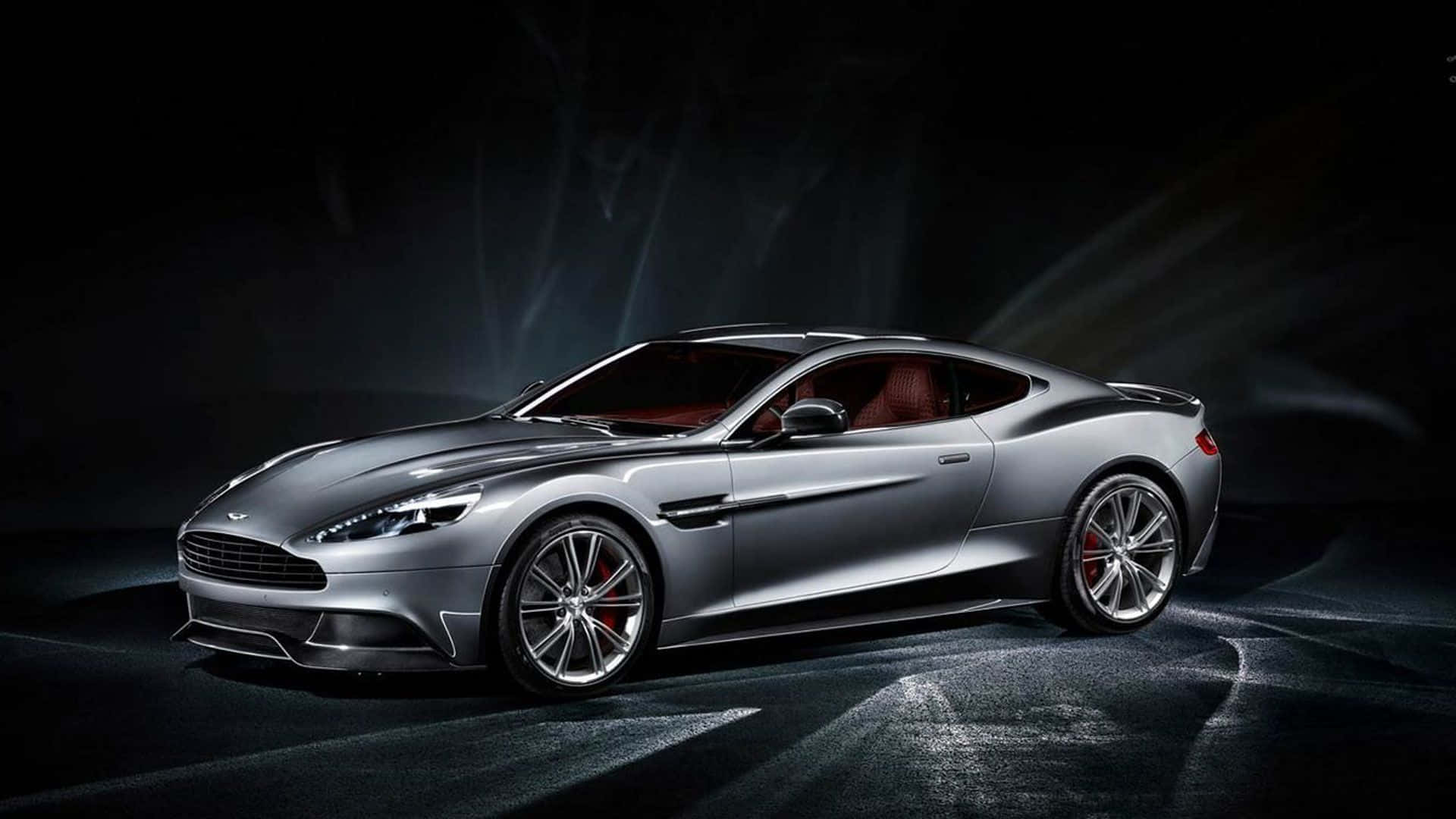 Aston Martin Vanquish 桌布 壁紙 — 一輛時尚的銀色Aston Martin跑車在戲劇性的工作室燈光下發光，背景是黑暗陰沉的背景。