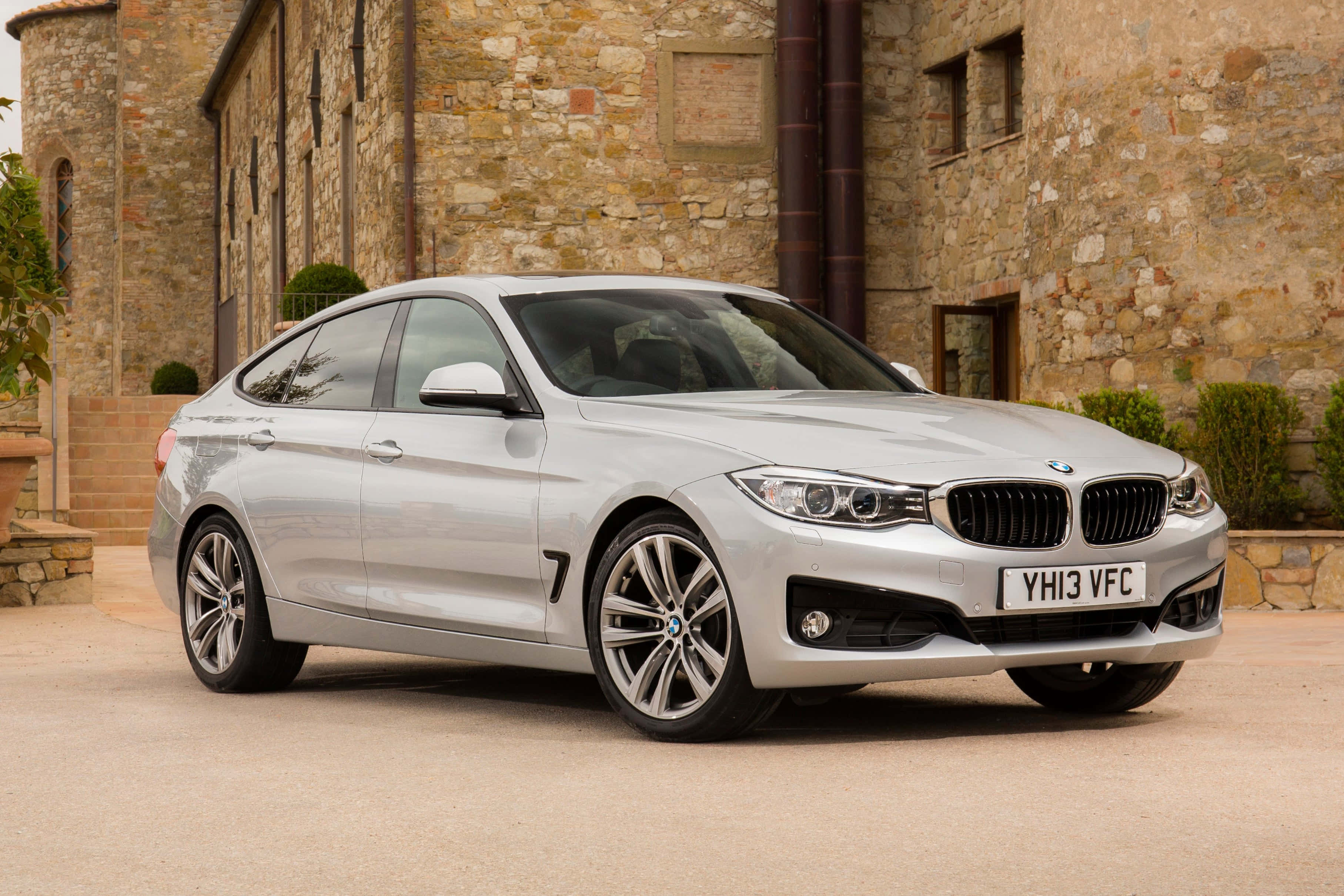 Bmw 3 Series 桌布 壁紙 — 一輛時尚的銀色BMW 3系列Gran Coupe停在質樸的石建築前，天氣晴朗。