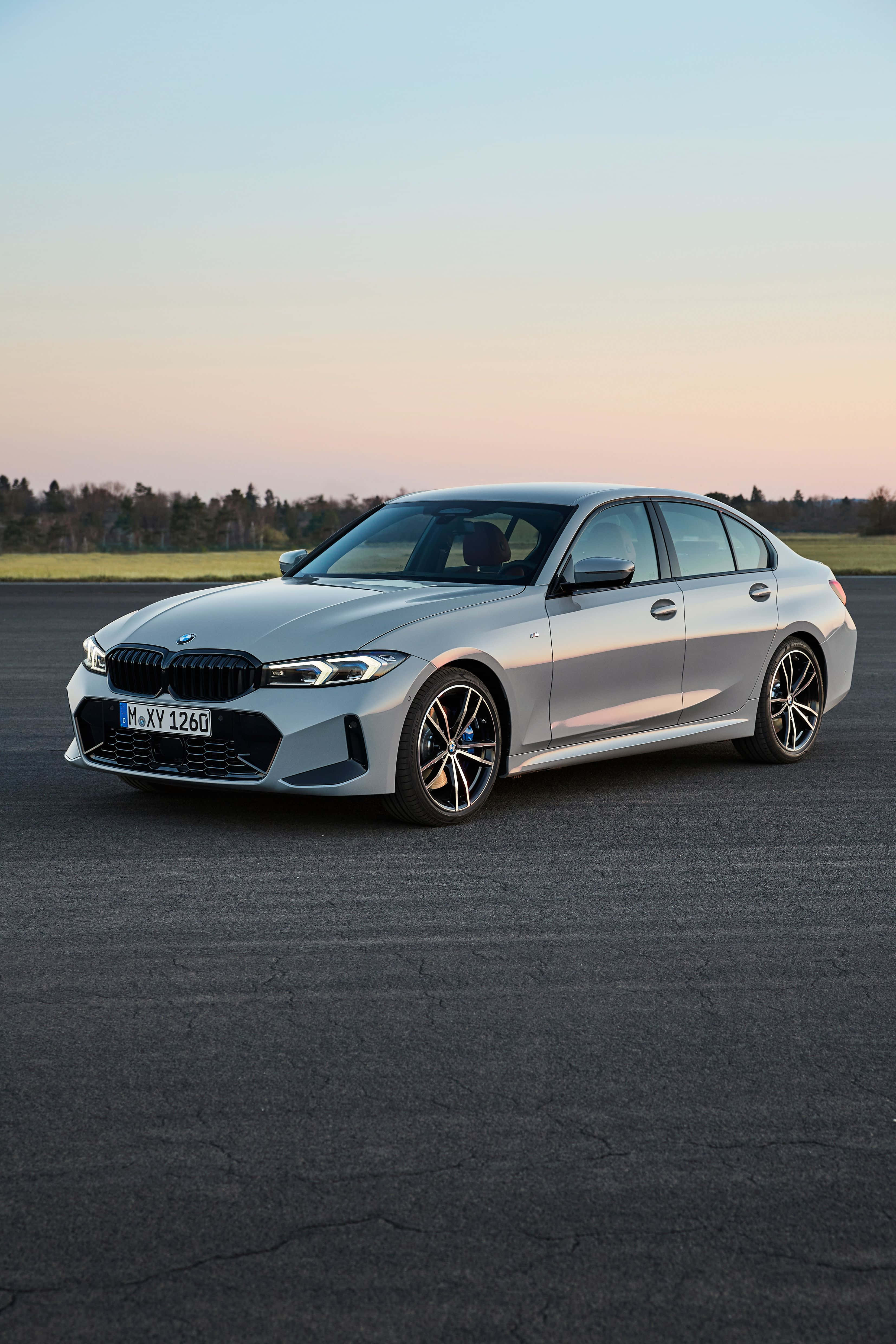 Bmw 328 桌布 壁紙 — 一輛時尚的銀色BMW 3系列轎車停在日落時分的瀝青停車場，背後是柔和漸層的天空。