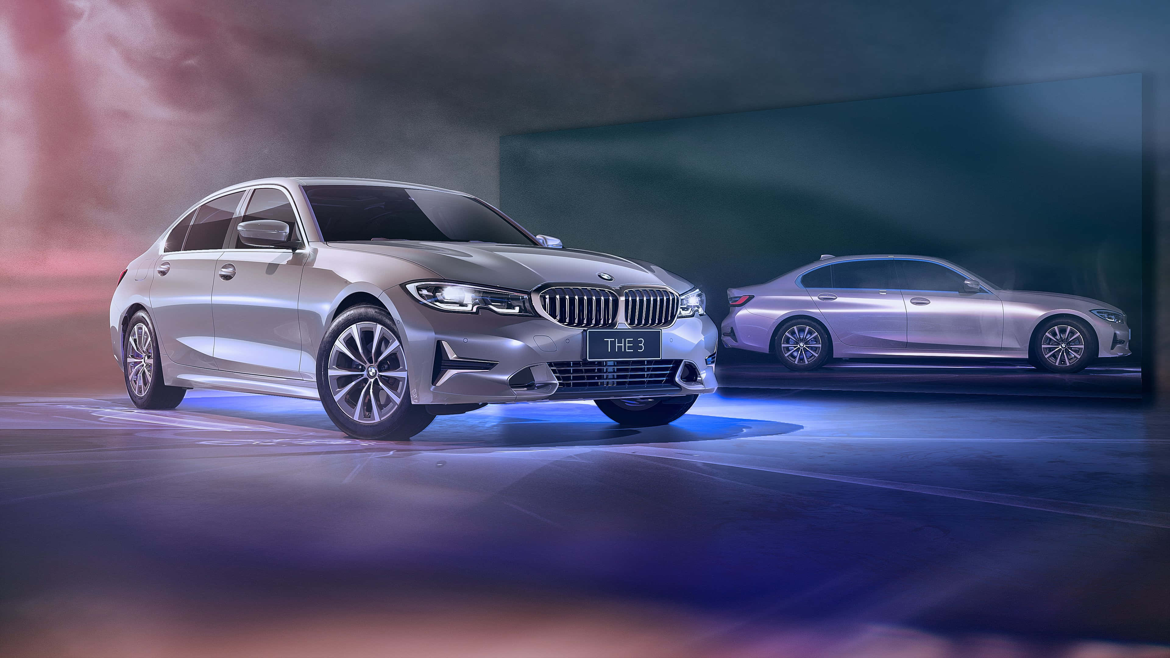 高清 桌布 壁紙 — 一輛時尚的銀色BMW 3系列轎車在戲劇性的藍色和粉紅色工作室燈光下閃耀，背後有半透明的倒影。