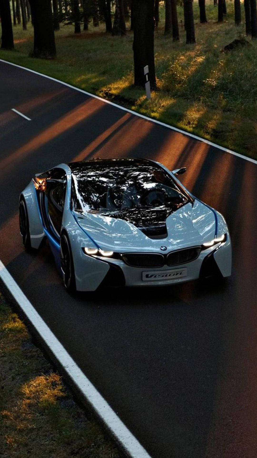 X 桌布 壁紙 — 一輛時尚的銀色BMW i8 Vision跑車沿著沐浴在金色日落光線中的森林道路滑行。