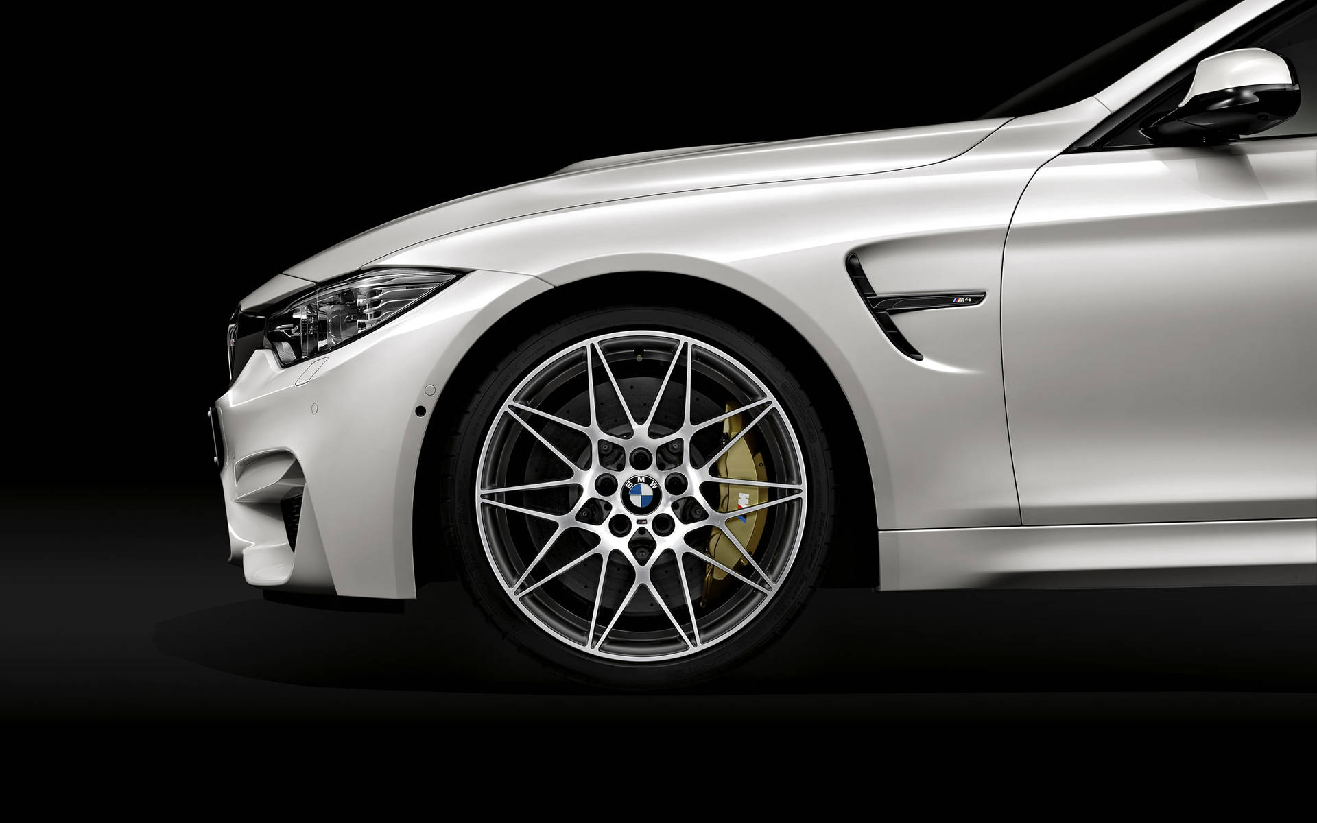 銀色BMW M4跑車，配備金色制動卡鉗和多輻輪圈，黑色背景。