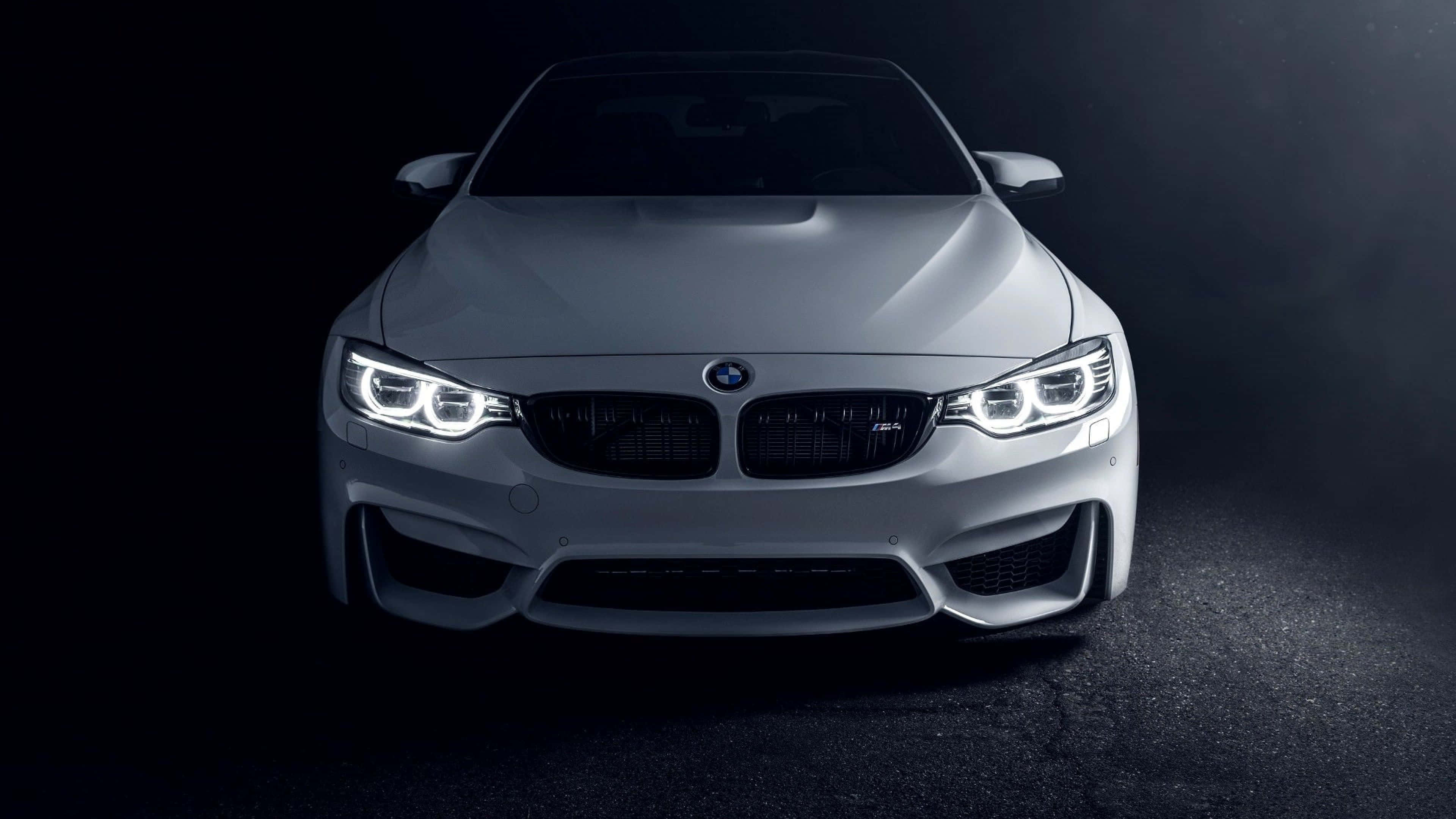 4K BMW 壁紙 桌布 壁紙 — 一輛時尚的銀色BMW M4跑車在黑暗的攝影棚背景下閃耀著銳利的LED頭燈。