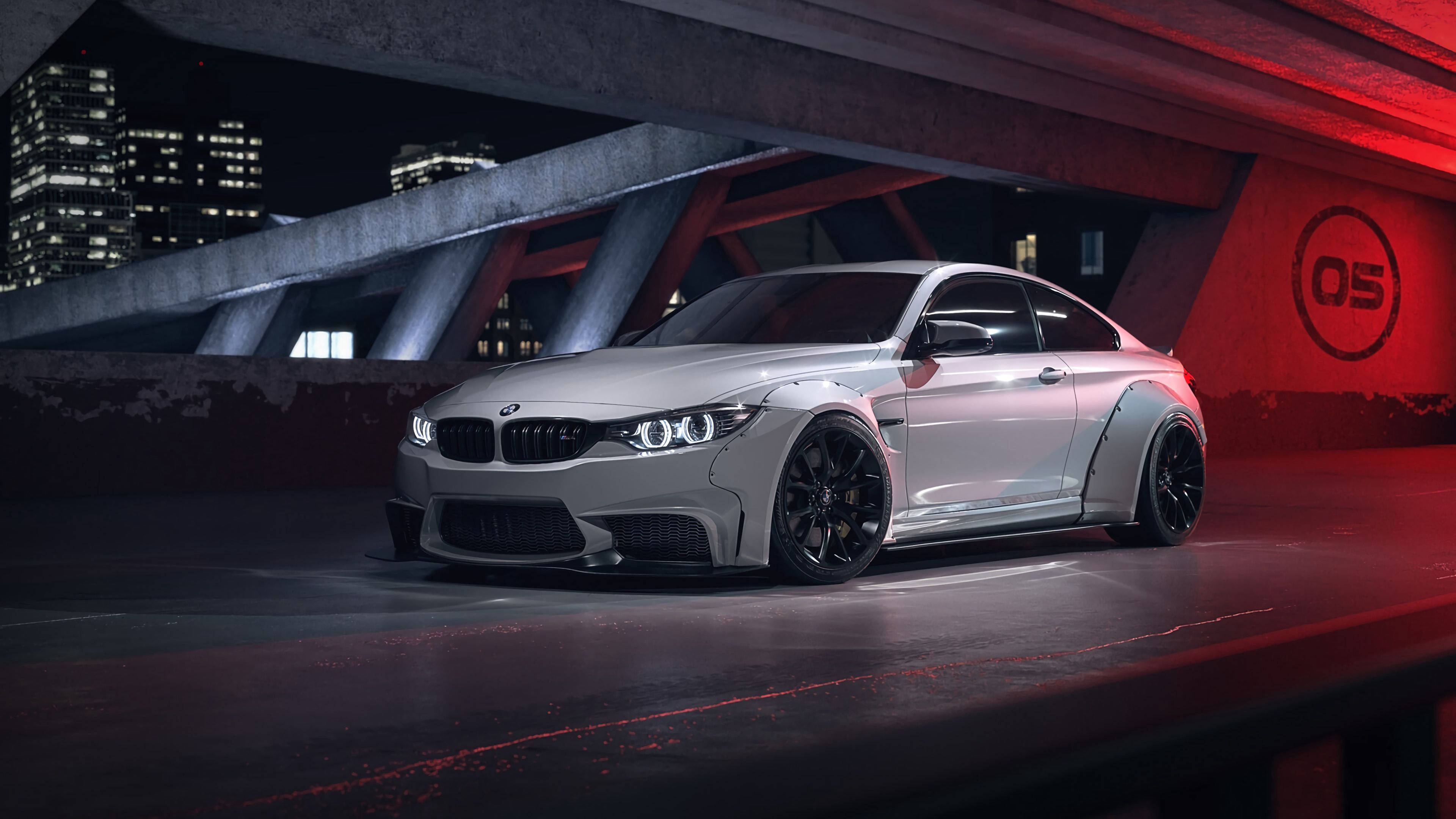 4K BMW 壁紙 桌布 壁紙 — 一輛時尚的銀色BMW M4雙門轎跑車，配備黑色輪圈，夜間停放在紅色燈光照射的城市天橋下，背景是城市燈光。