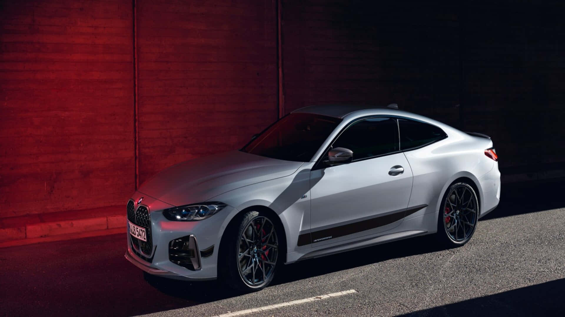汽車 桌布 壁紙 — 一輛時尚的銀色BMW M4雙門轎跑車停在發光的紅磚牆前，燈光效果戲劇化。