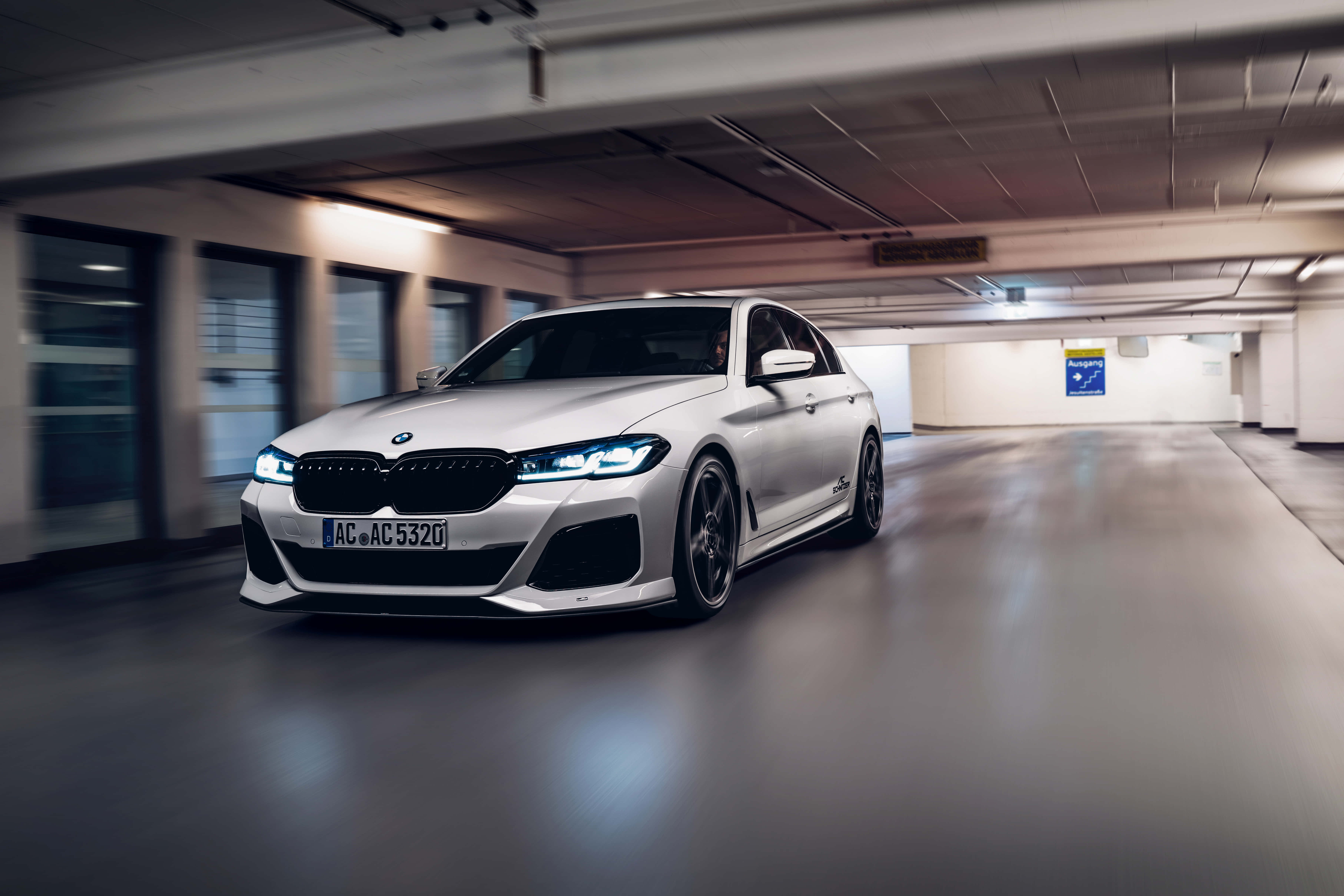 桌布 壁紙 — 一輛時尚的銀色BMW M5在地下停車場高速行駛，周圍環境呈現動態模糊效果。