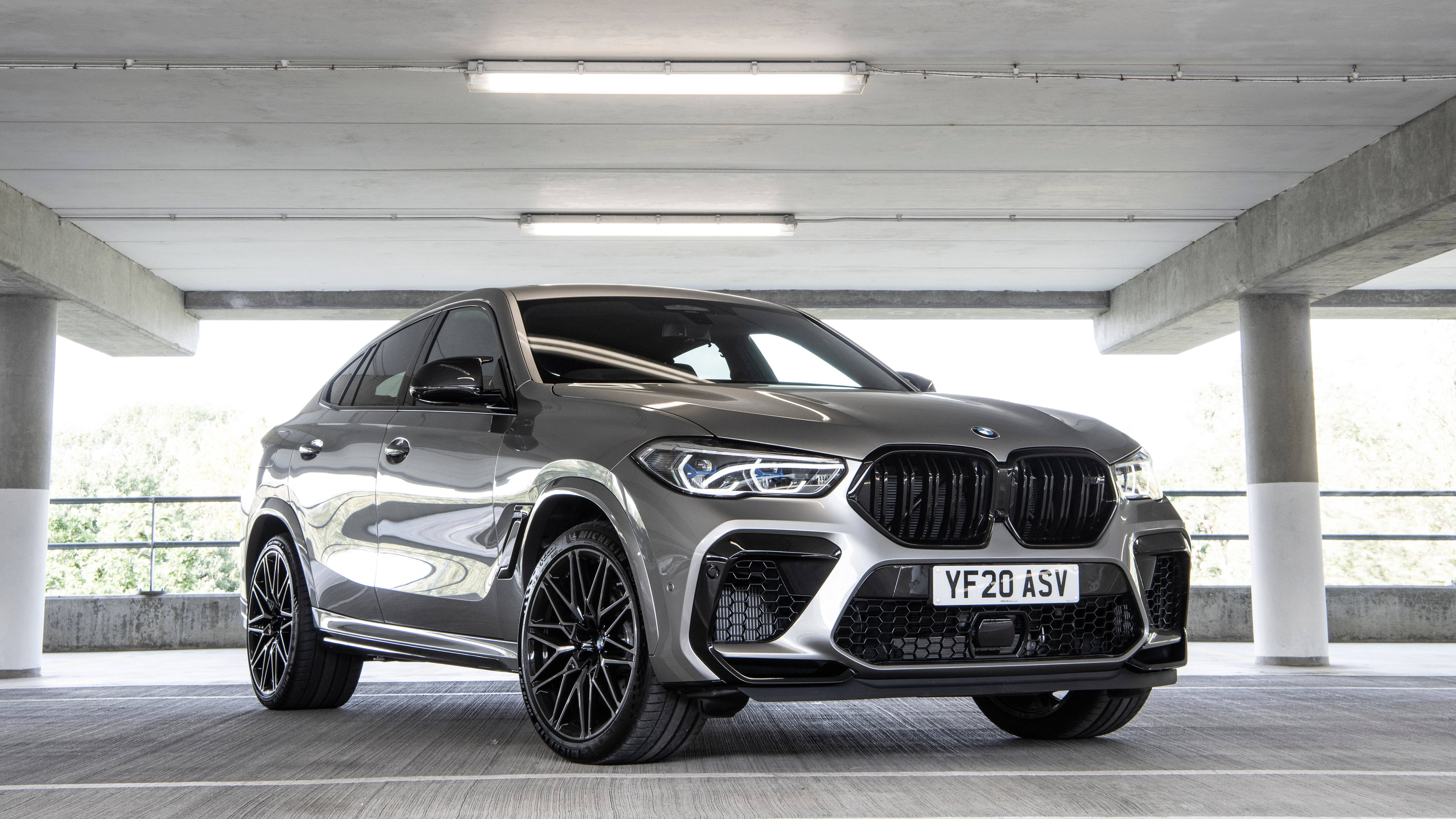 m 桌布 壁紙 — 一輛時尚的銀色BMW X6 M停在混凝土停車場下，明亮的頂燈反射在其拋光表面上。