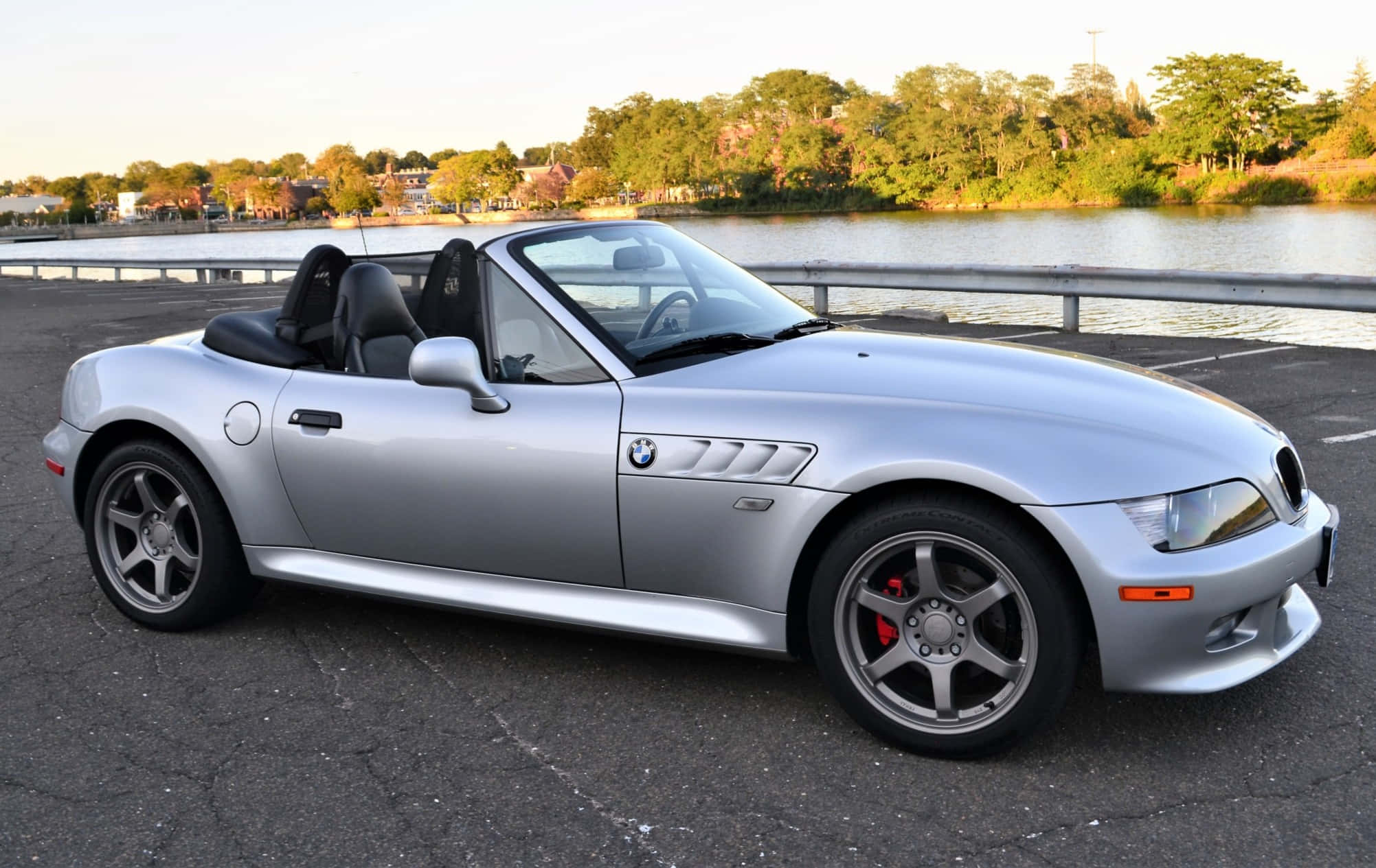Bmw Z3 桌布 壁紙 — 一輛時尚的銀色BMW Z8敞篷車在黃金時段停泊在海濱，背景有樹木。