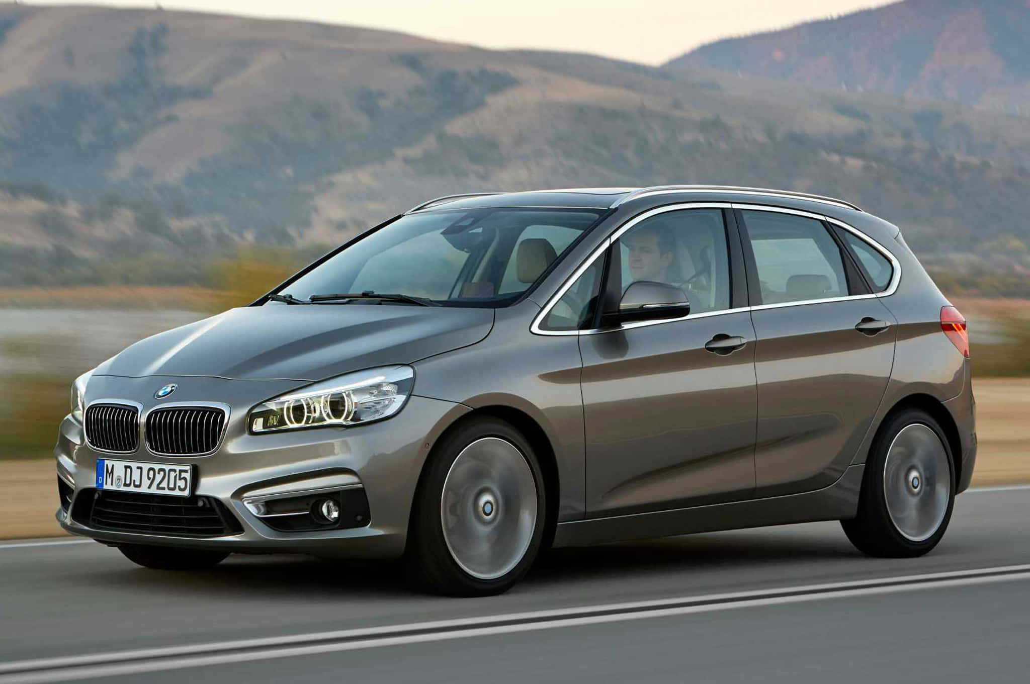 Bmw 2 Series 桌布 壁紙 — 一輛時尚的銀色BMW旅行車在高速公路上行駛，背景是模糊的山丘。