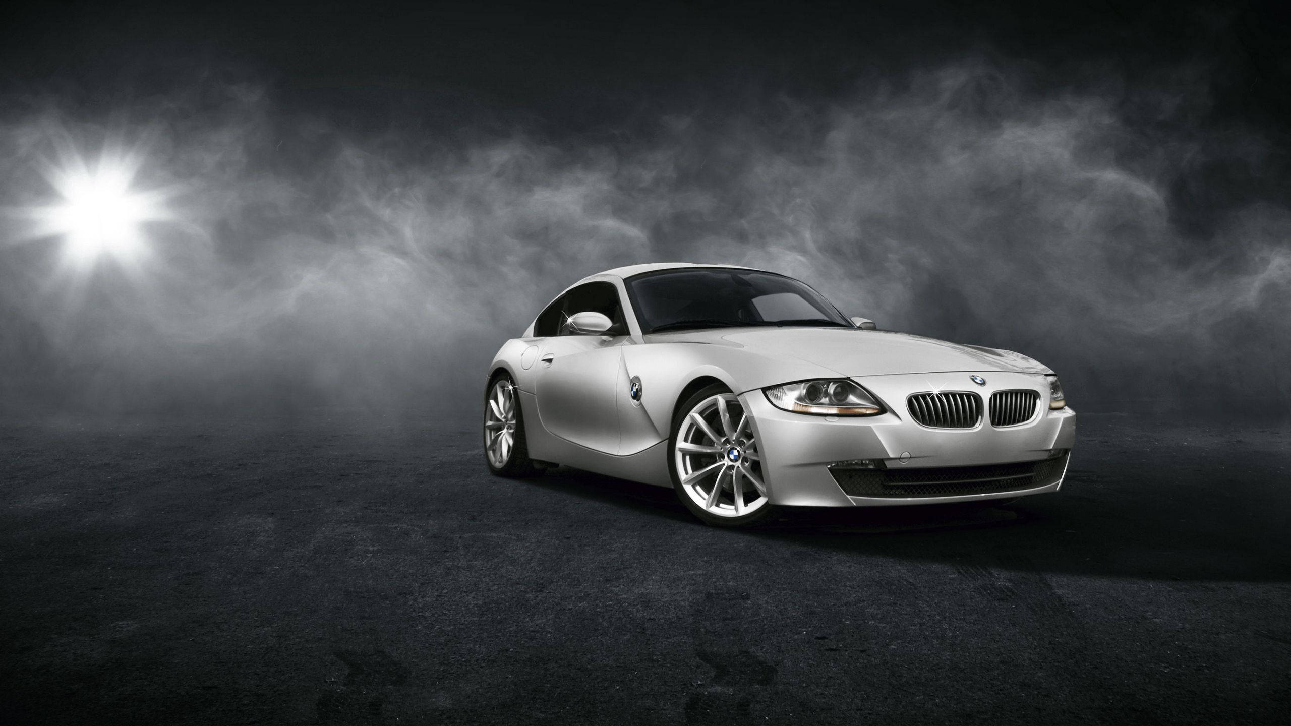BMW 動圖 桌布 壁紙 — 一輛時尚的銀色BMW跑車在黑色瀝青表面上，於旋轉的黑暗煙霧中，在聚光燈下閃耀。