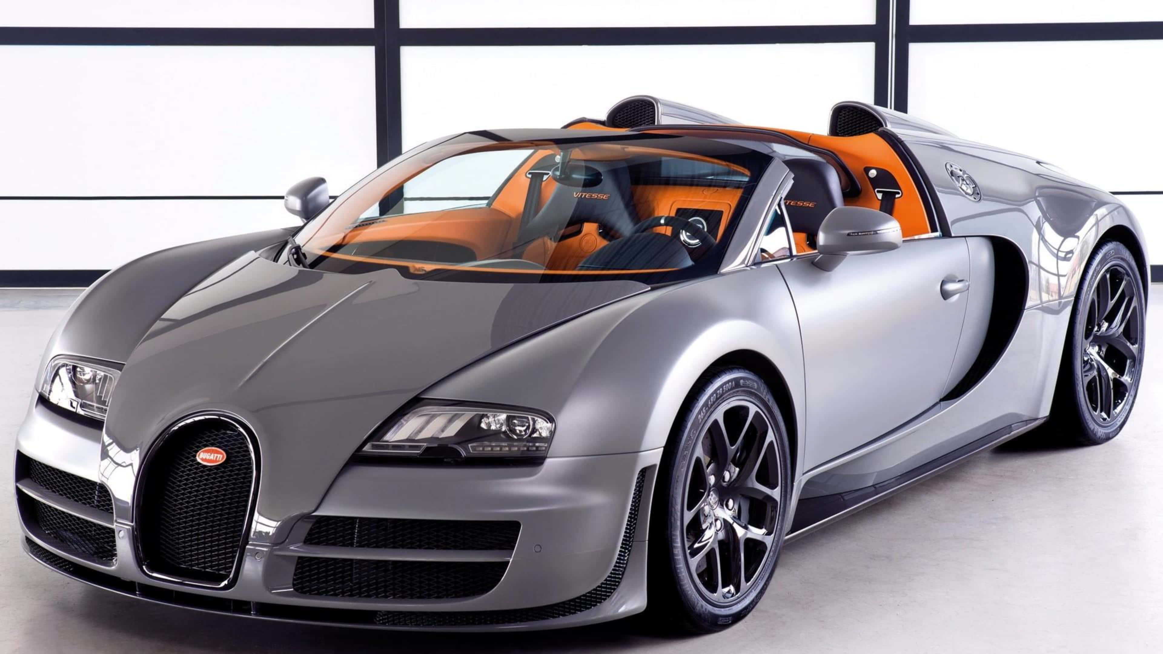 bugatti iPhone 桌布 壁紙 — 一輛時尚的銀色Bugatti Veyron Grand Sport，配以充滿活力的橙色內裝，停放在一個設有大窗戶的簡約工作室中。