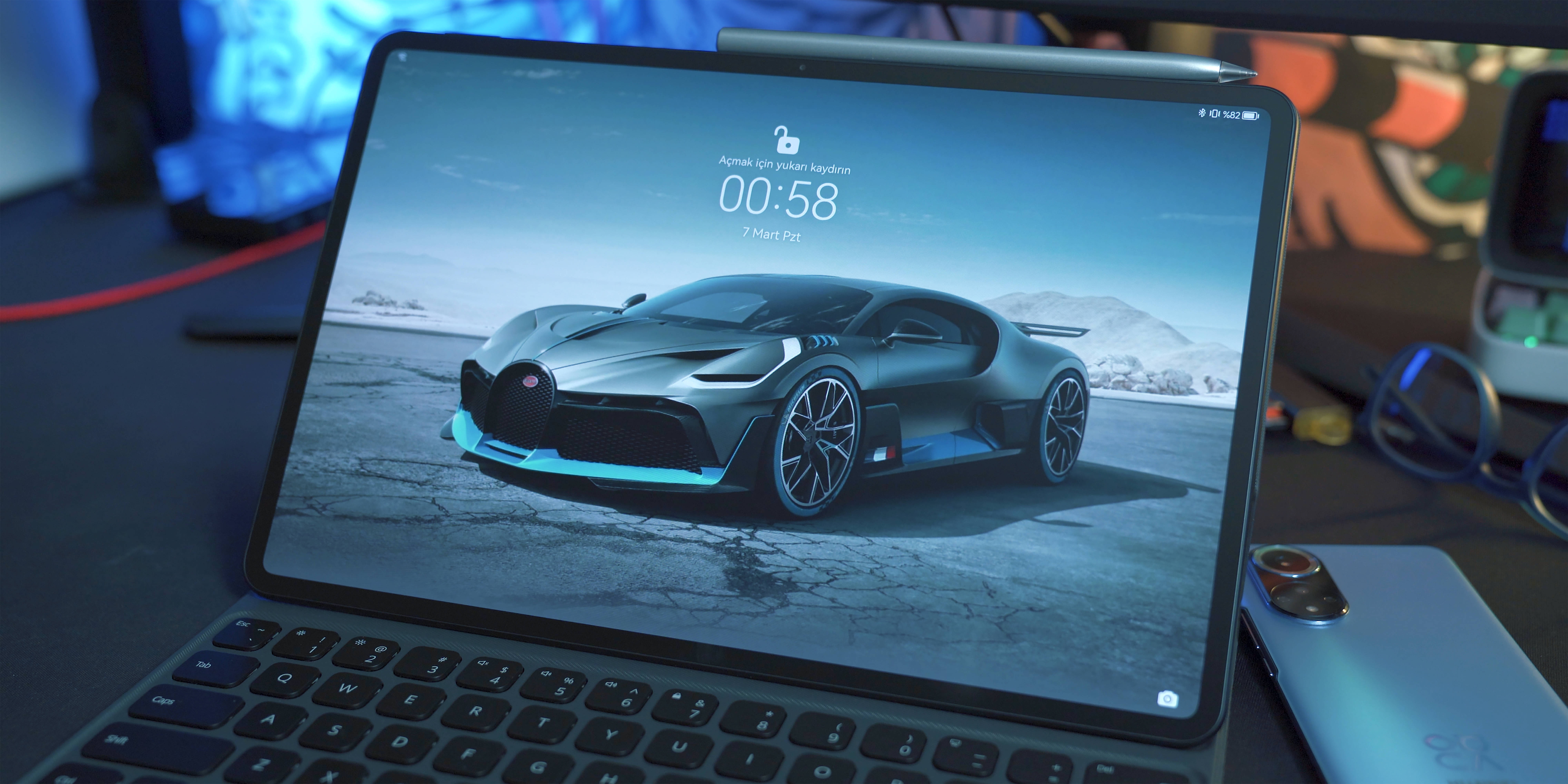 bugatti iPhone 桌布 壁紙 — 一輛時尚的銀色Bugatti超跑，帶有發光的藍色點綴，在平板電腦螢幕上，位於晴朗天空下龜裂的沙漠地面上。