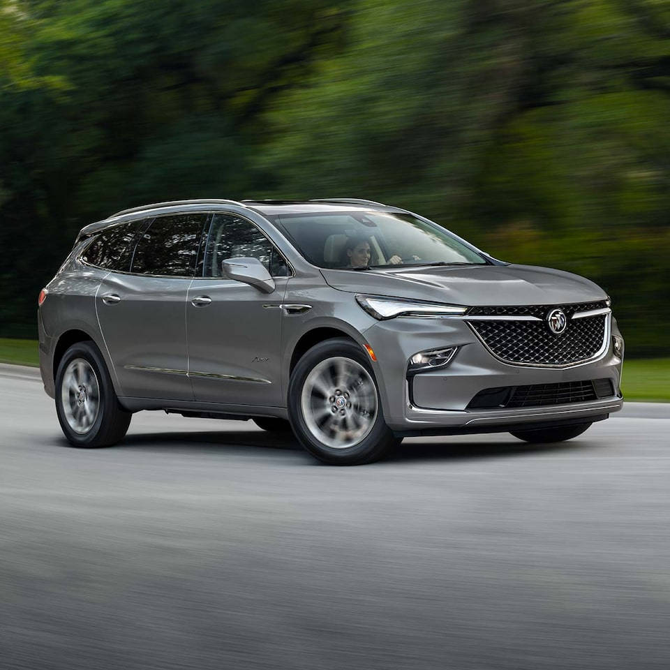 Buick 桌布 壁紙 — 一輛時尚的銀色Buick SUV在道路上疾馳，背景是模糊的綠色樹木。