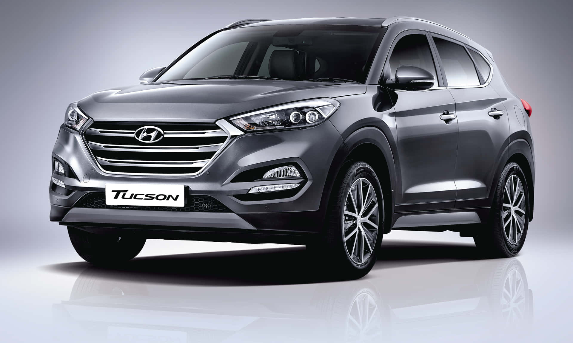 Hyundai 桌布 壁紙 — 一輛時尚的銀色Hyundai Tucson SUV在帶有反射地板和柔和漸變背景的攝影棚中展示。