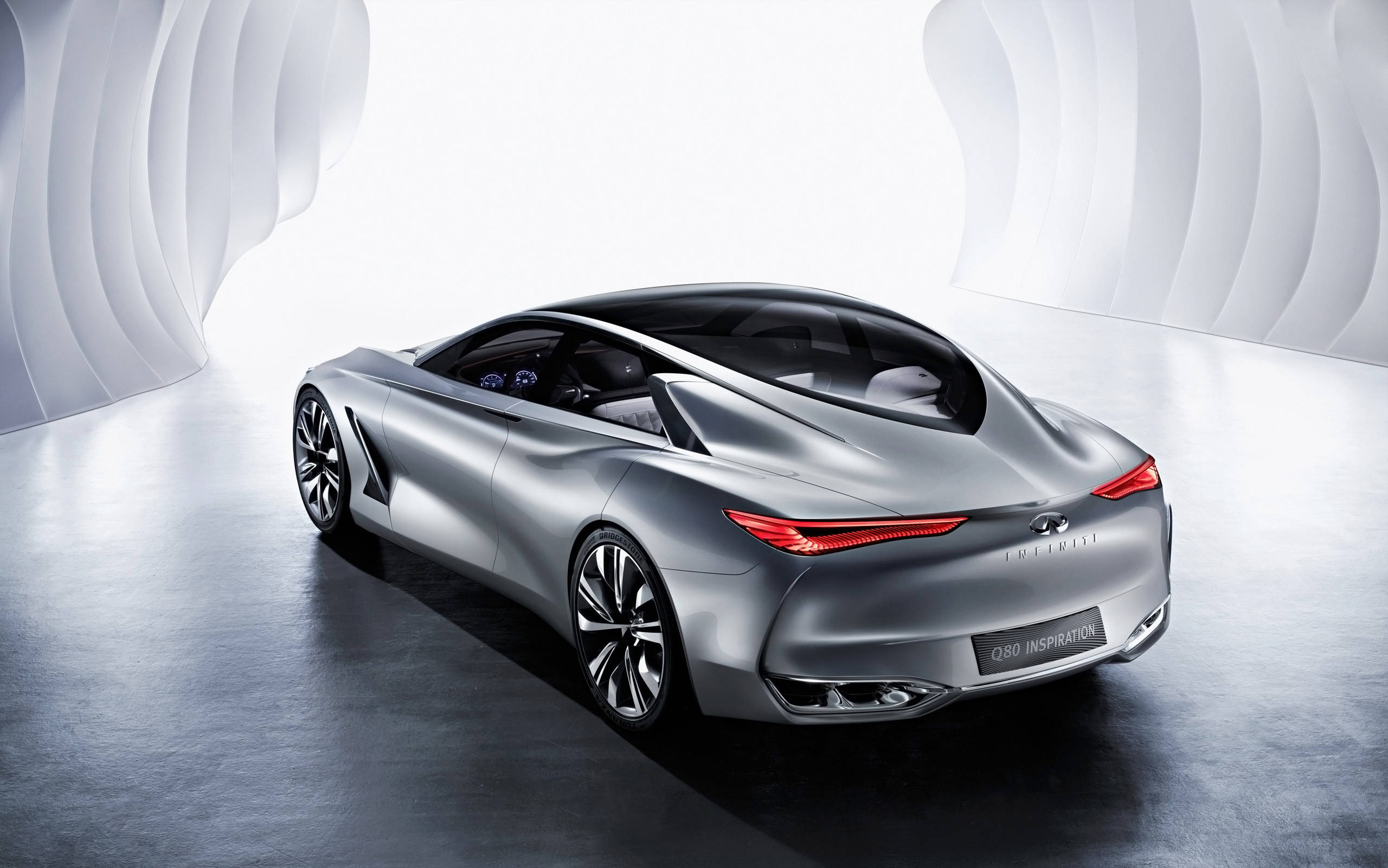 Infiniti 桌布 壁紙 — 一輛時尚的銀色Infiniti Q80 Inspiration概念車，帶有發光的紅色尾燈，在未來主義的白色彎曲隧道中展示。