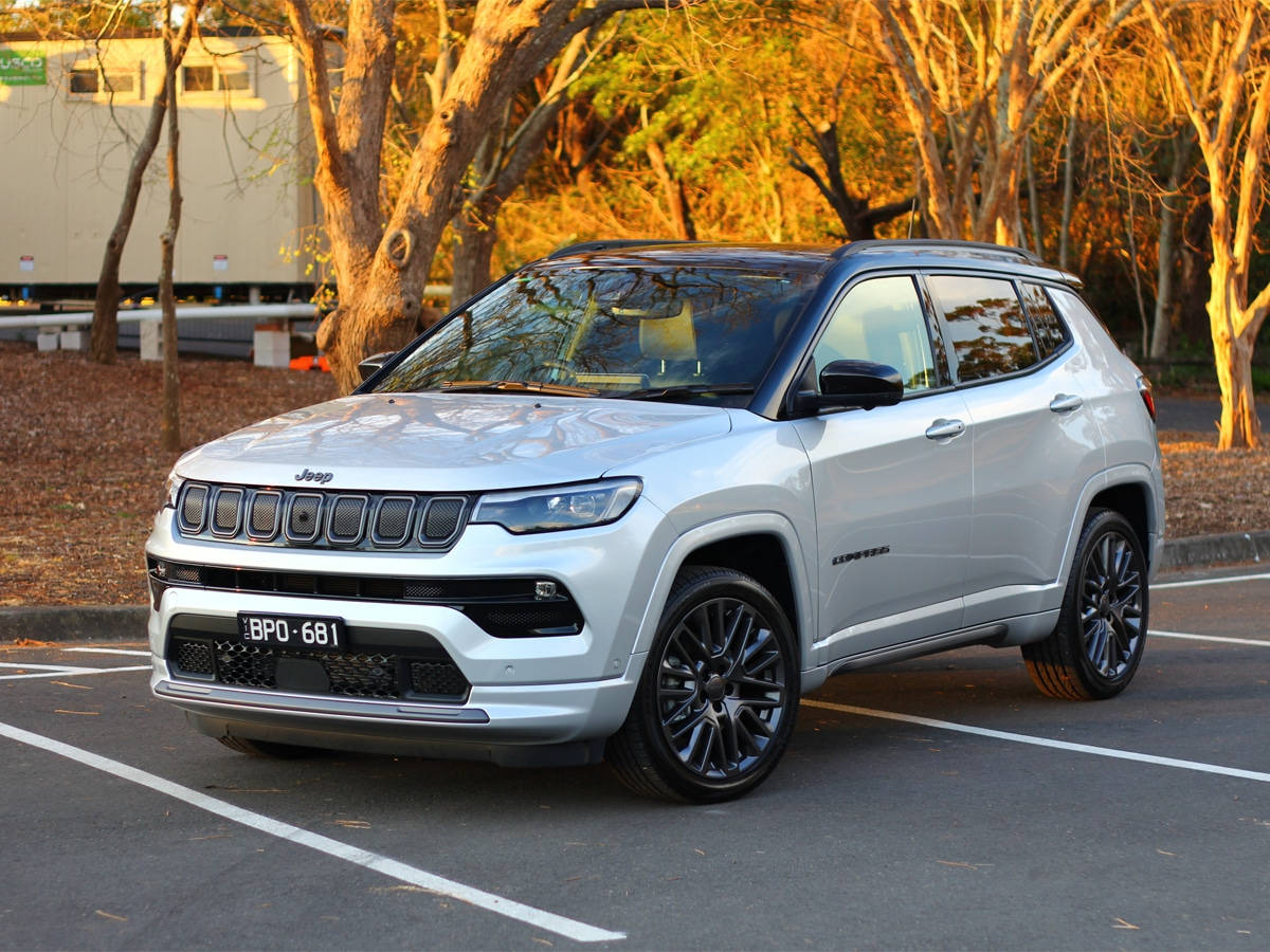 秋天動圖 桌布 壁紙 — 一輛時尚的銀色Jeep Compass停放在陽光普照的停車場，周圍是金黃色的秋樹。