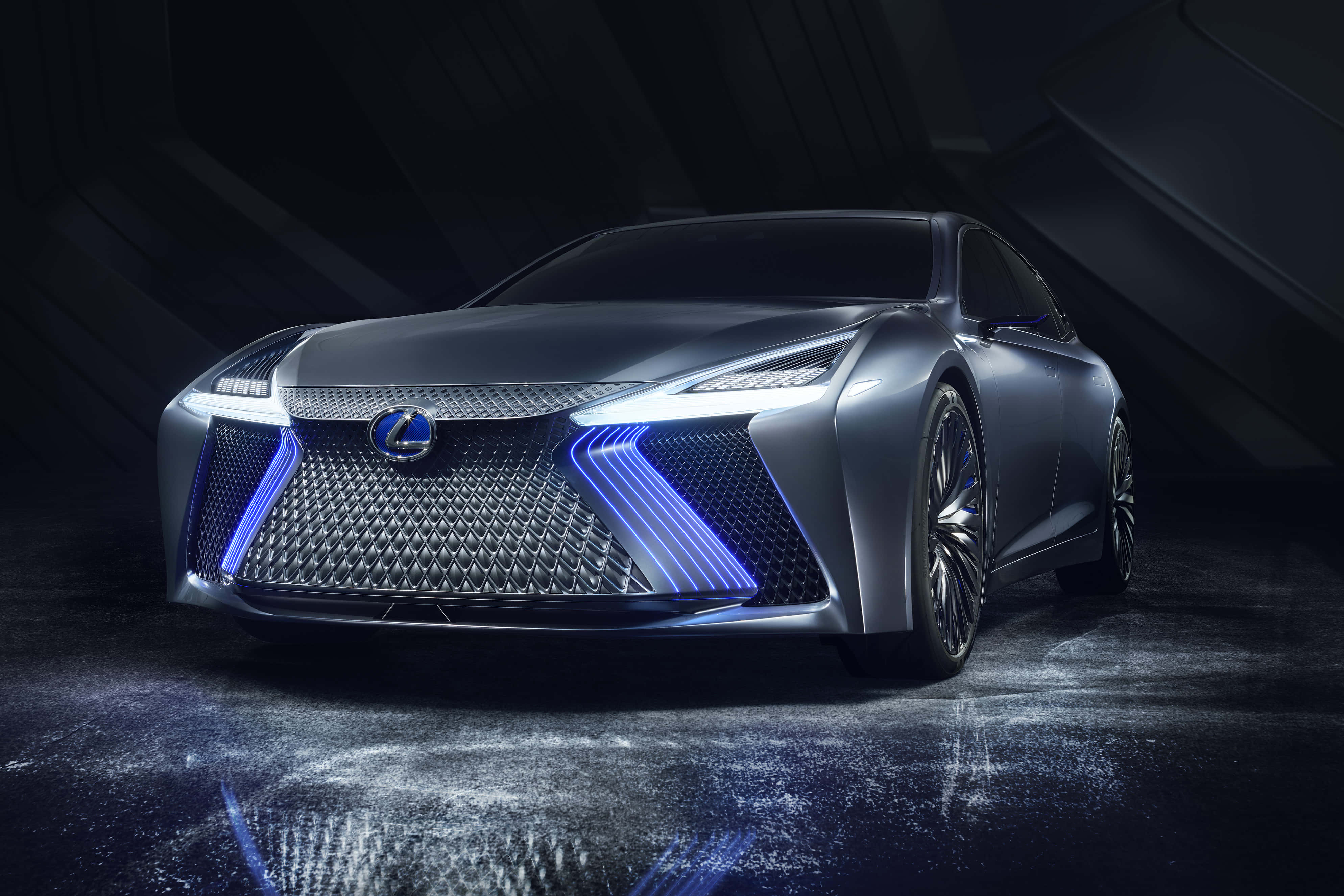 高清 桌布 壁紙 — 一輛時尚的銀色Lexus概念車，帶有發光的藍色頭燈和格柵，戲劇性地矗立在一個黑暗、有棱角且帶有反射性濕地板的攝影棚中。