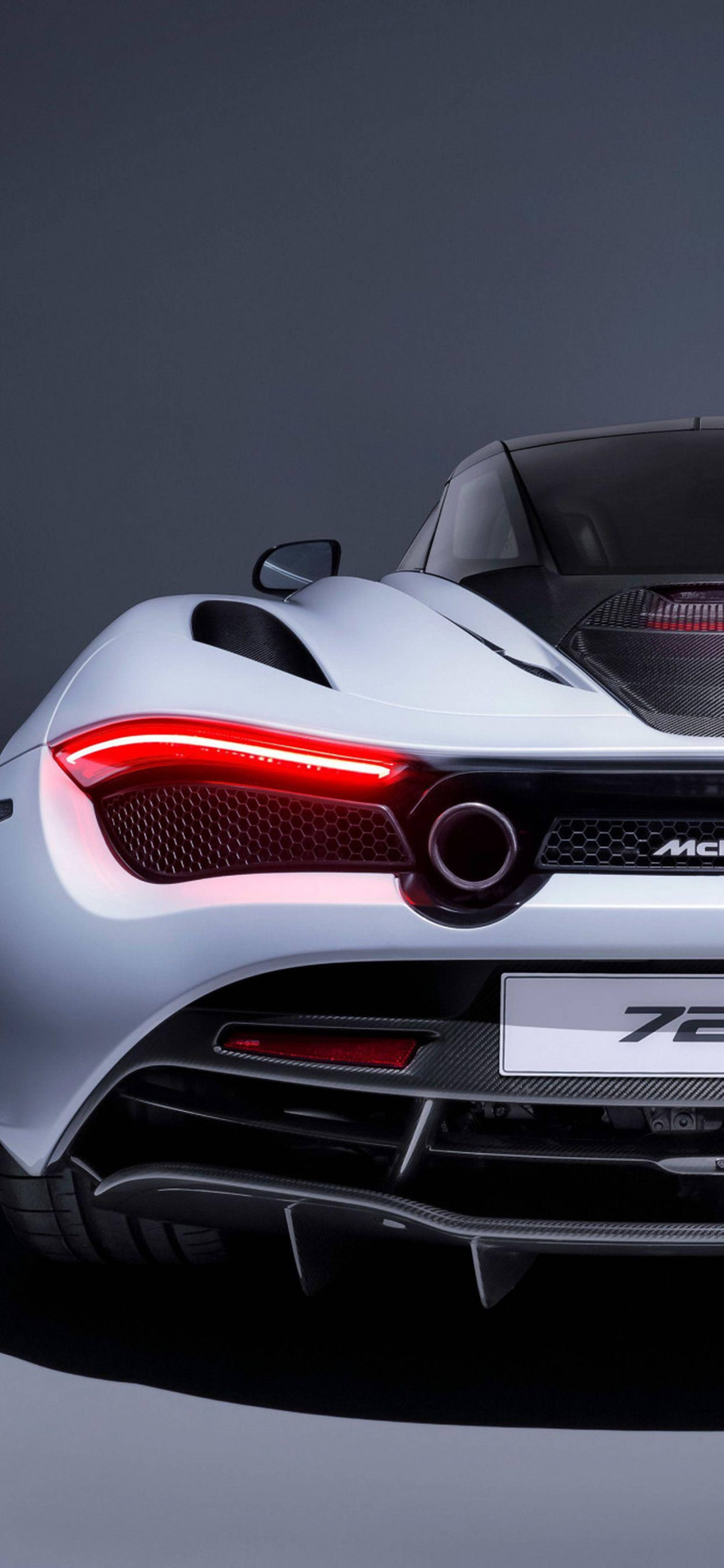 Luxury 桌布 壁紙 — 一輛時尚的銀色McLaren 720S跑車後視圖，帶有發光的紅色尾燈，背景為深色工作室。