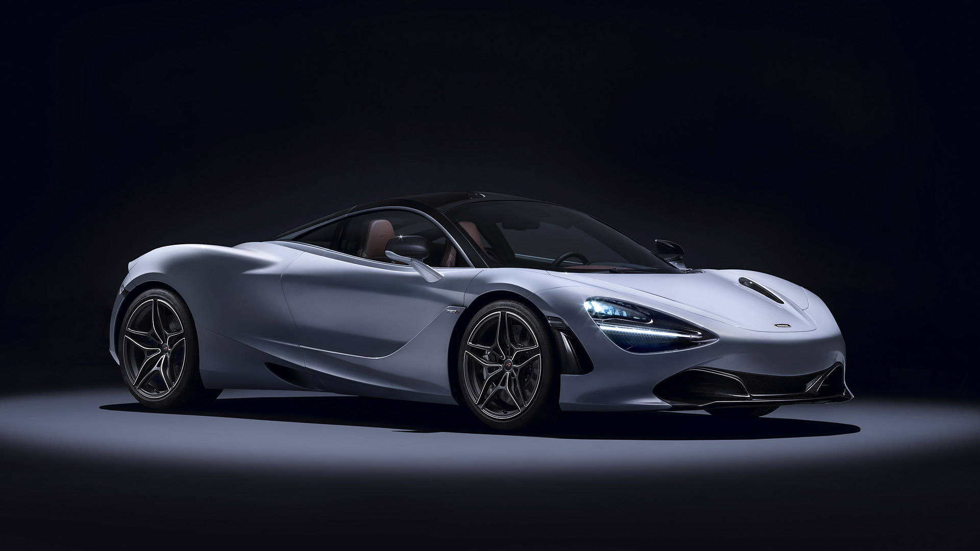 mclaren 720s 4K 桌布 壁紙 — 一輛時尚的銀色McLaren 720S跑車在黑色背景下的戲劇性工作室燈光中閃耀。