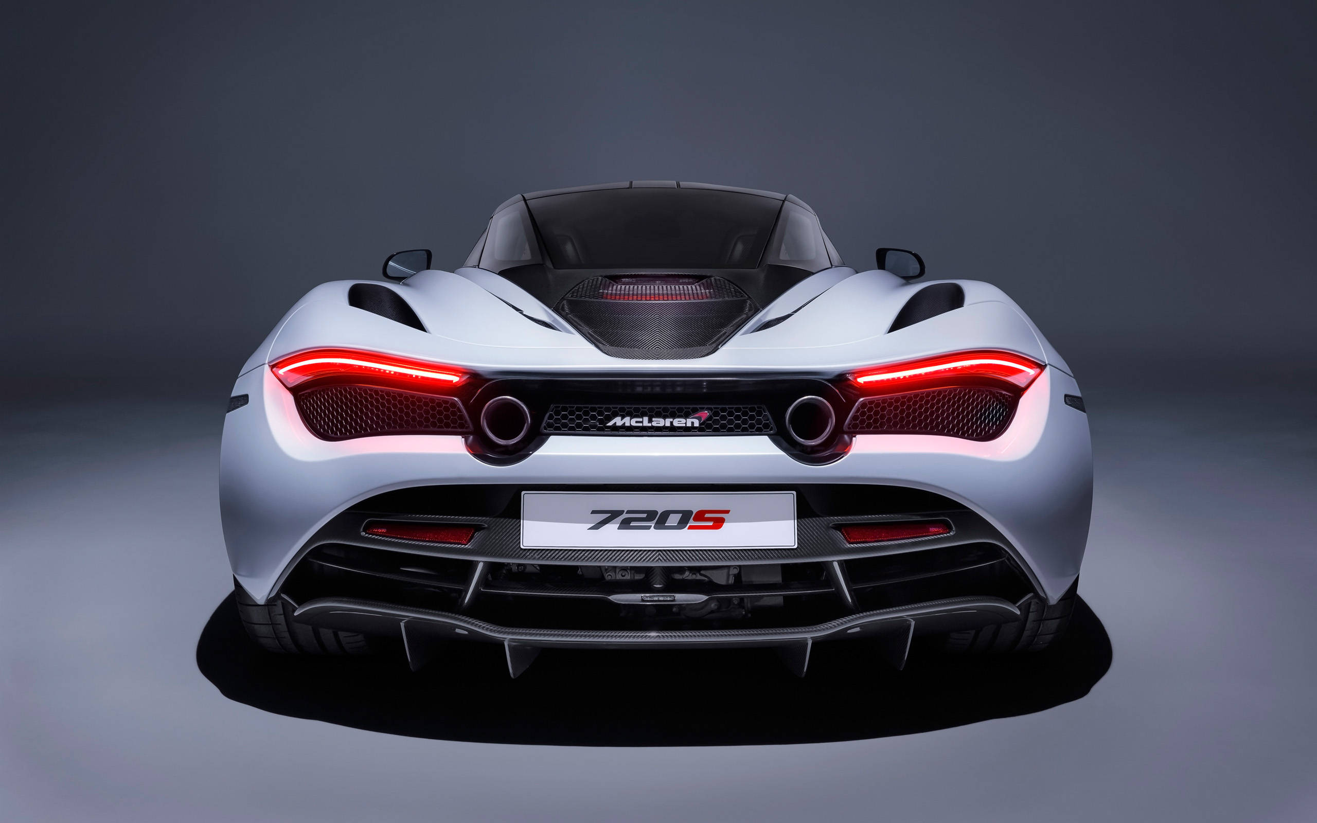 mclaren 720s 4K 桌布 壁紙 — 一輛時尚的銀色McLaren 720S跑車，從後方觀看，帶有發光的紅色尾燈，背景為深色攝影棚。