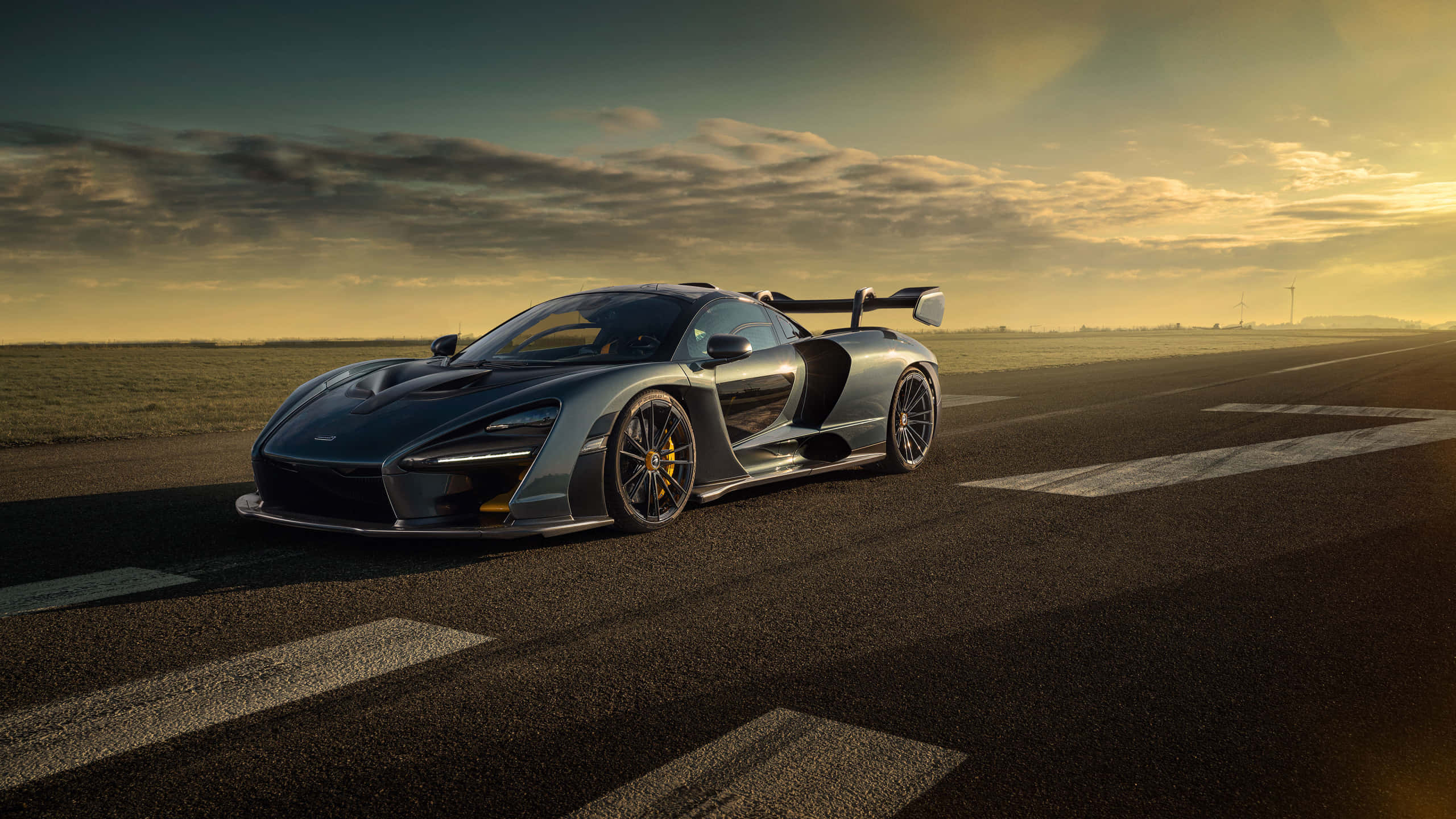 桌布 壁紙 — 一輛時尚的銀色McLaren Senna跑車在黃金時段滑行在跑道上，頭頂有戲劇性的雲層。