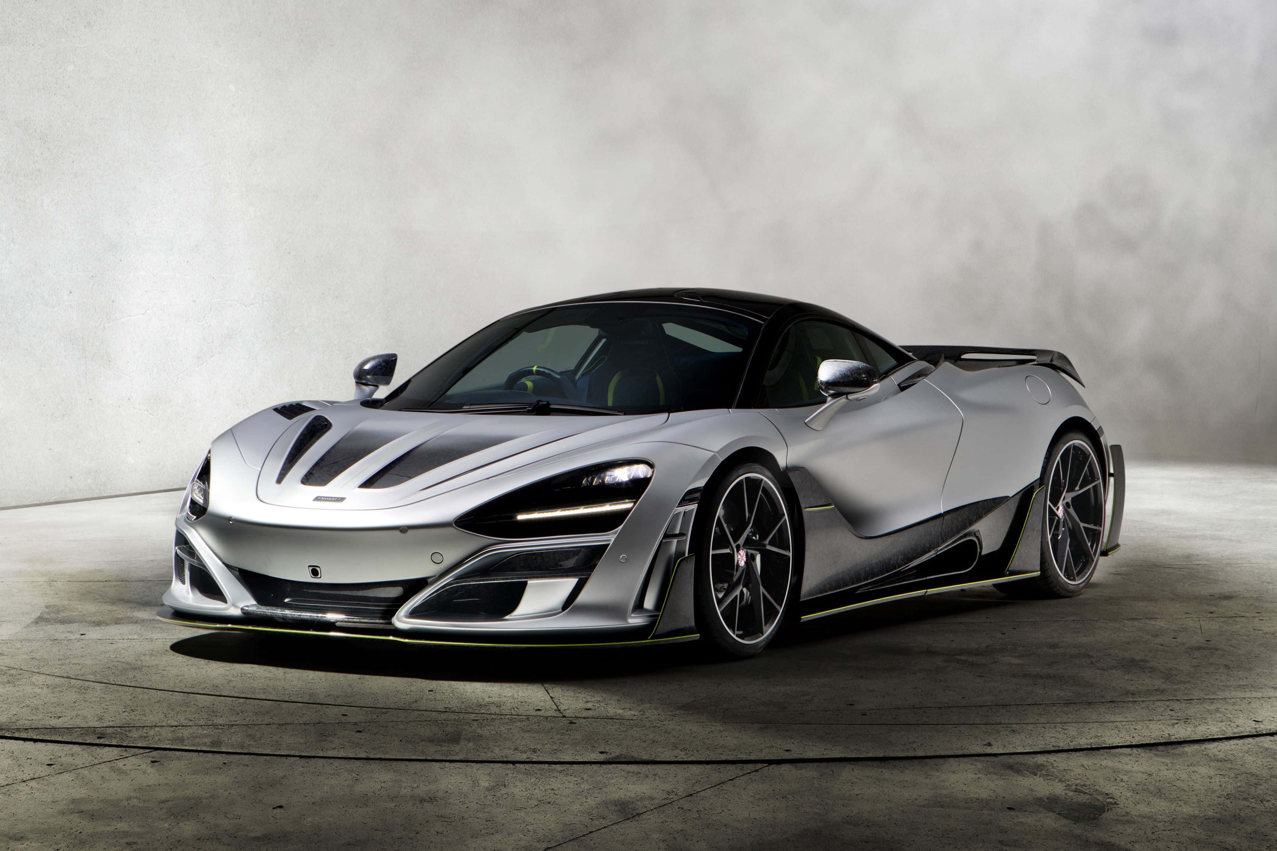 Mclaren 720s 桌布 壁紙 — 一輛時尚的銀色McLaren超級跑車，帶有黑色點綴和黃色飾邊，在極簡主義的混凝土工作室中，在戲劇性的燈光下展示。