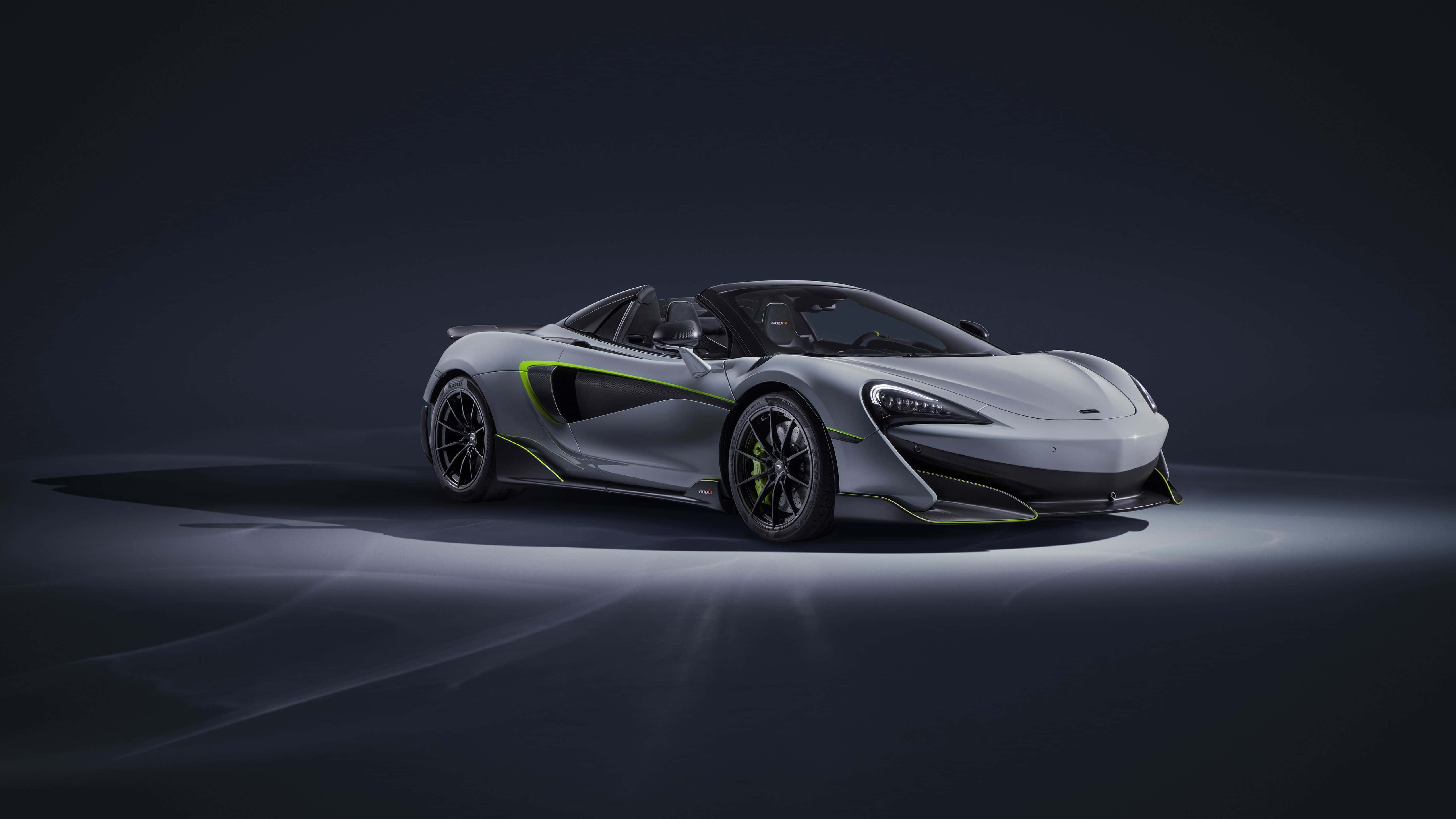 Mclaren 600lt 桌布 壁紙 — 一輛時尚的銀色McLaren跑車帶有螢光綠色點綴，在黑暗背景下的戲劇性工作室燈光中閃耀。