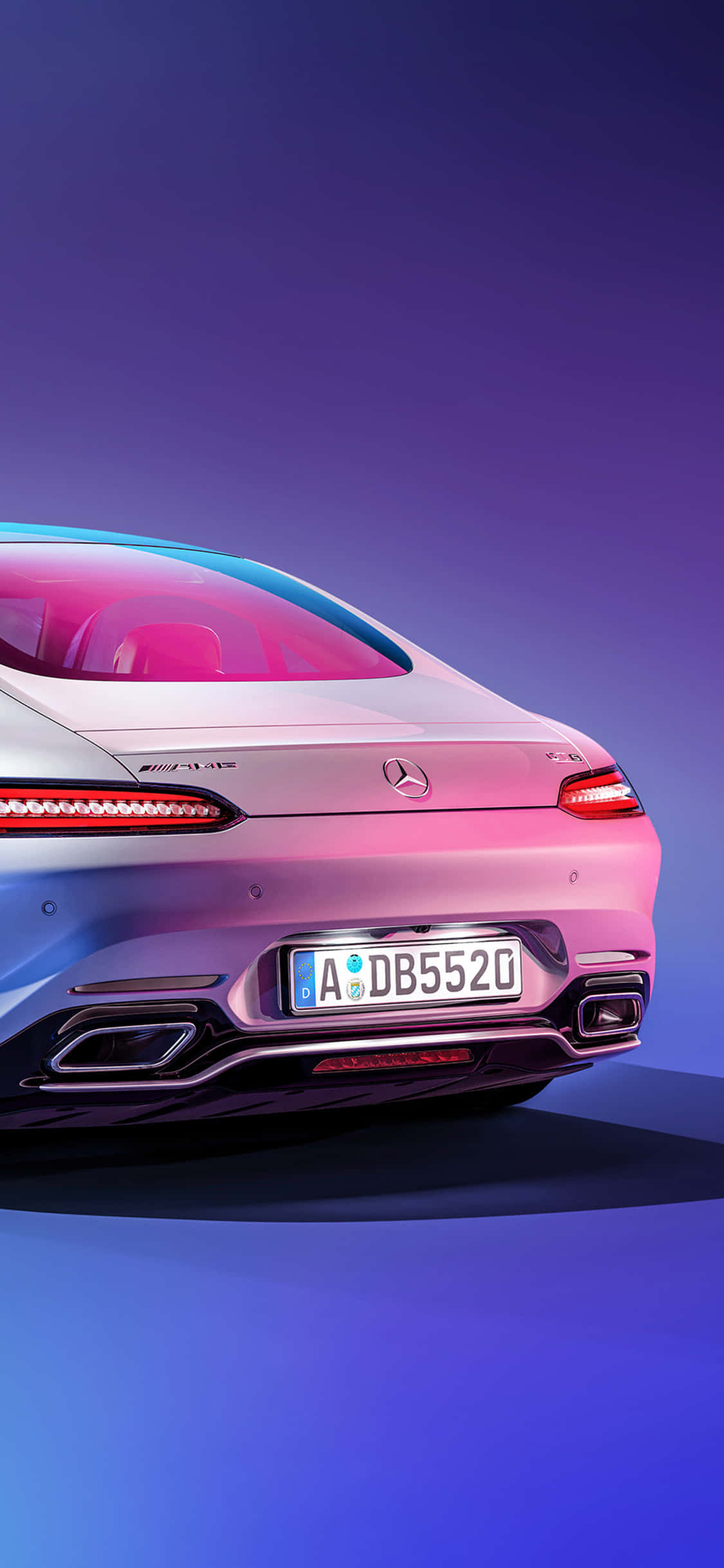 Trunk 桌布 壁紙 — 一輛時尚的銀色Mercedes-AMG S 63轎車在充滿活力的紫色和藍色工作室燈光下閃耀，展示其後部設計和運動型排氣管。