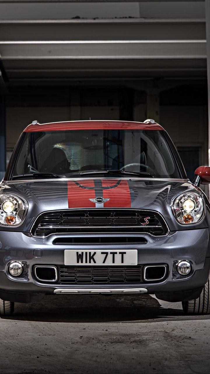 Mini Cooper 桌布 壁紙 — 一輛時尚的銀色Mini Countryman S，帶紅色車頂和賽車條紋，停放在混凝土車庫結構下。