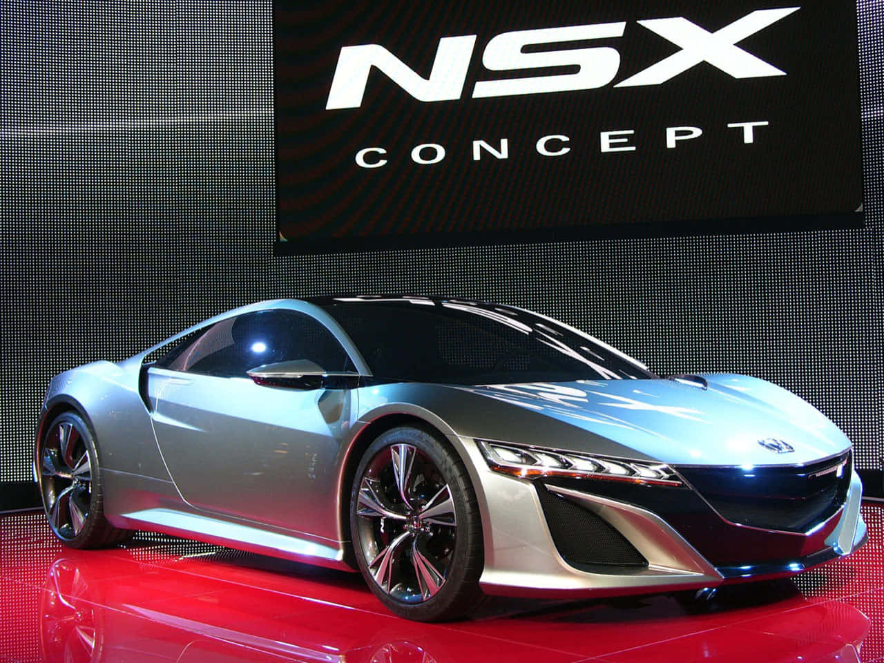 Honda Nsx 桌布 壁紙 — 一輛時尚的銀色NSX概念跑車在車展的紅色反光平台上，在明亮燈光下閃閃發光。