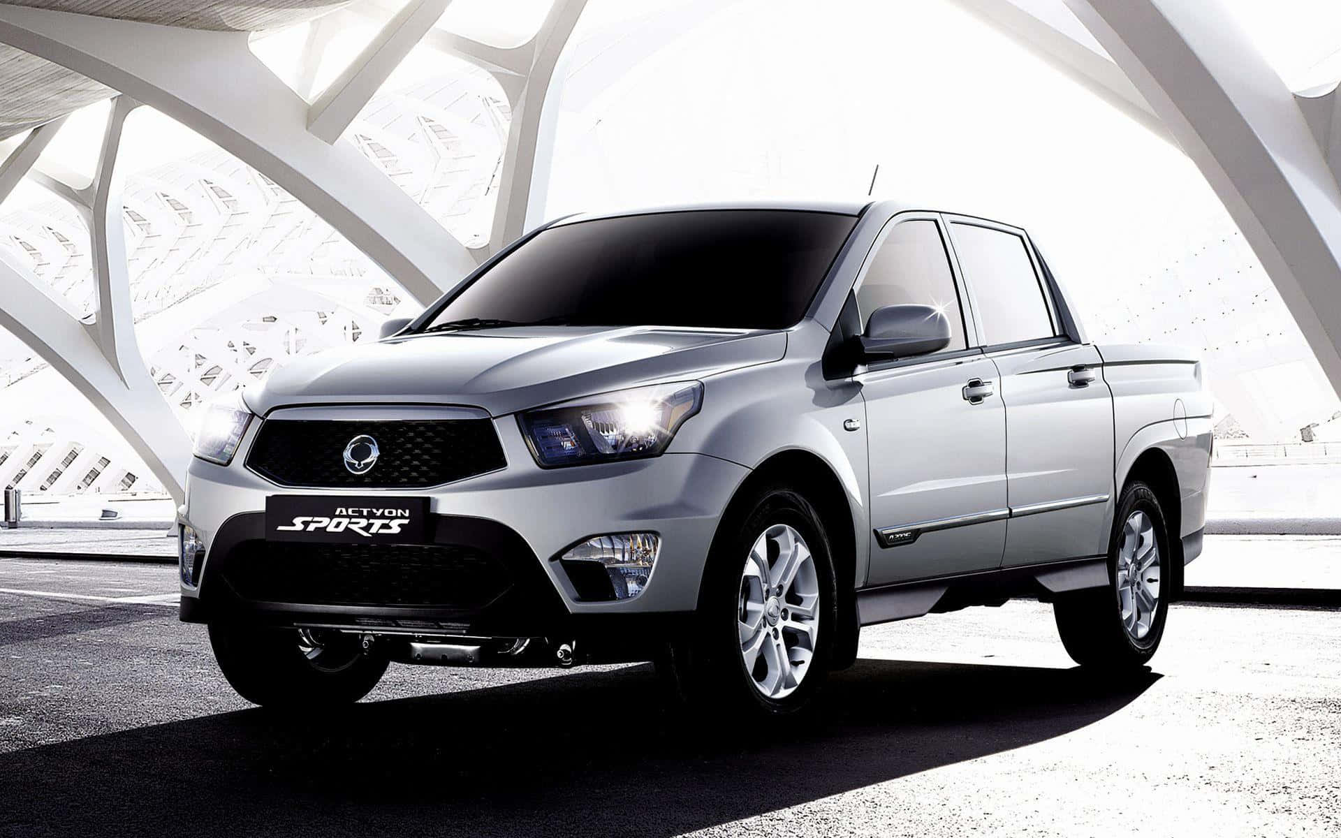 Ssangyong 桌布 壁紙 — 一輛時尚的銀色SsangYong Actyon Sports皮卡車停放在一座具有銳利幾何線條的現代白色建築結構下。