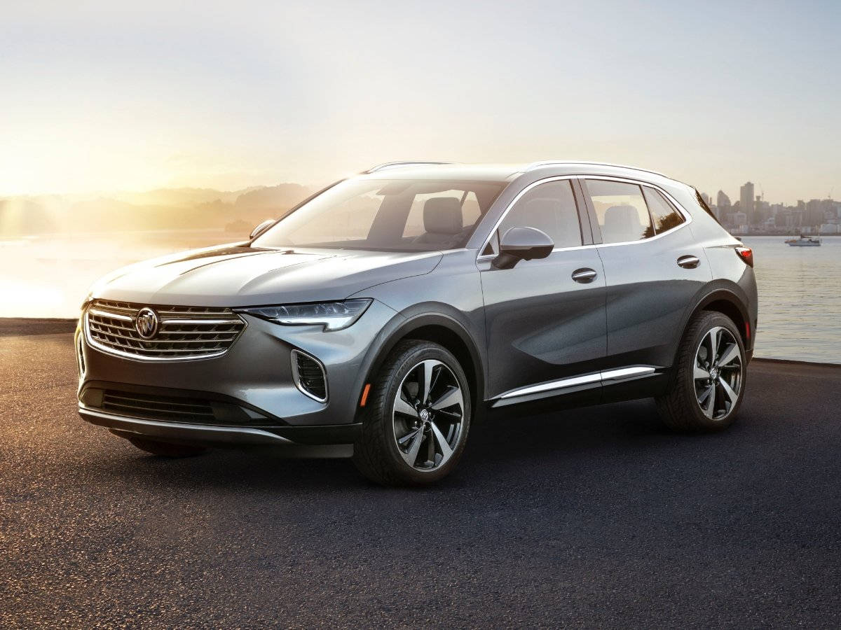 Buick 桌布 壁紙 — 一輛時尚的銀色SUV停在水邊，背景是金色日落時分的城市天際線。