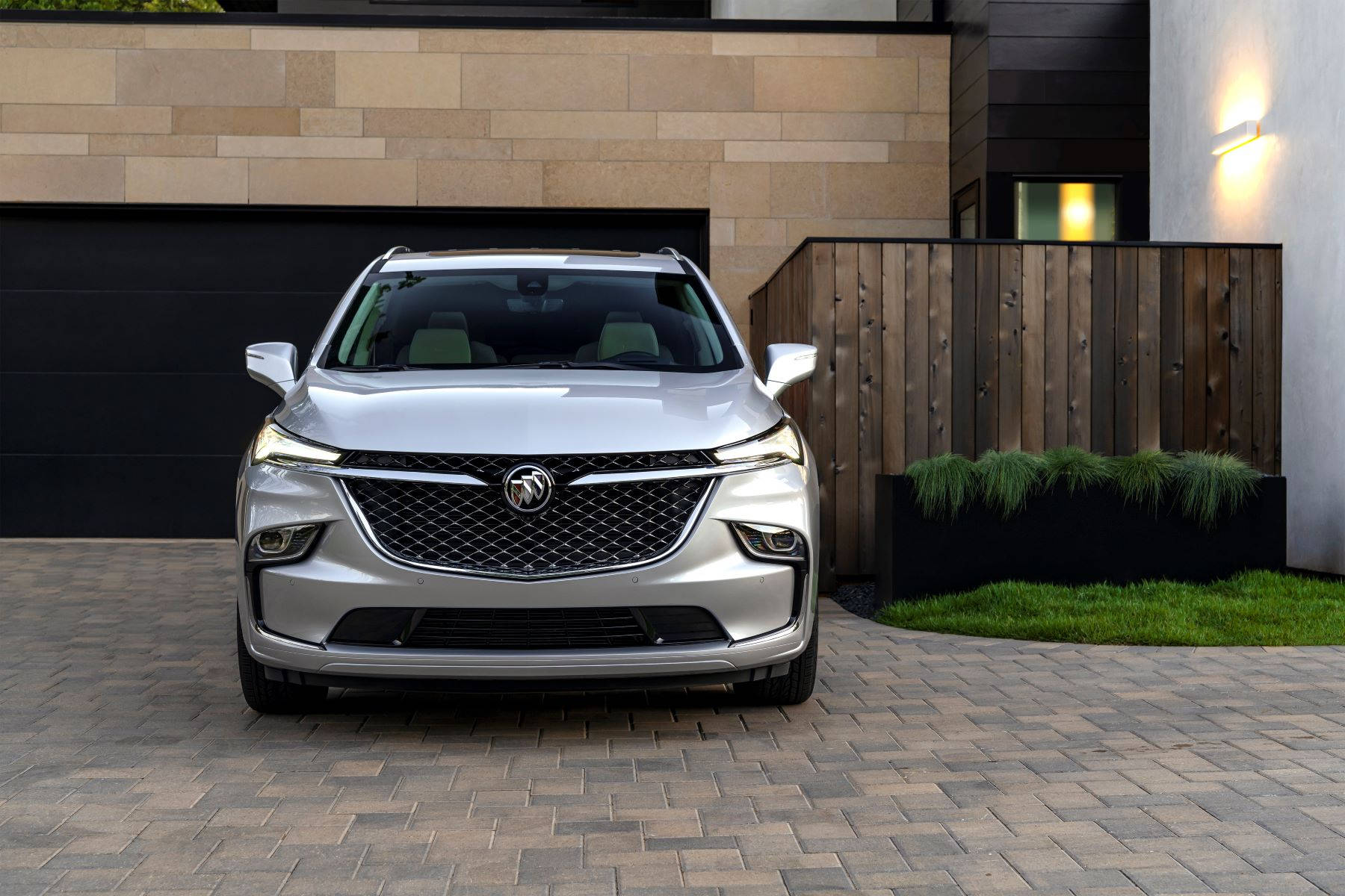 Buick 桌布 壁紙 — 一輛時尚的銀色SUV停在磚砌車道上，前面是帶有溫暖照明和木柵欄的現代房屋。