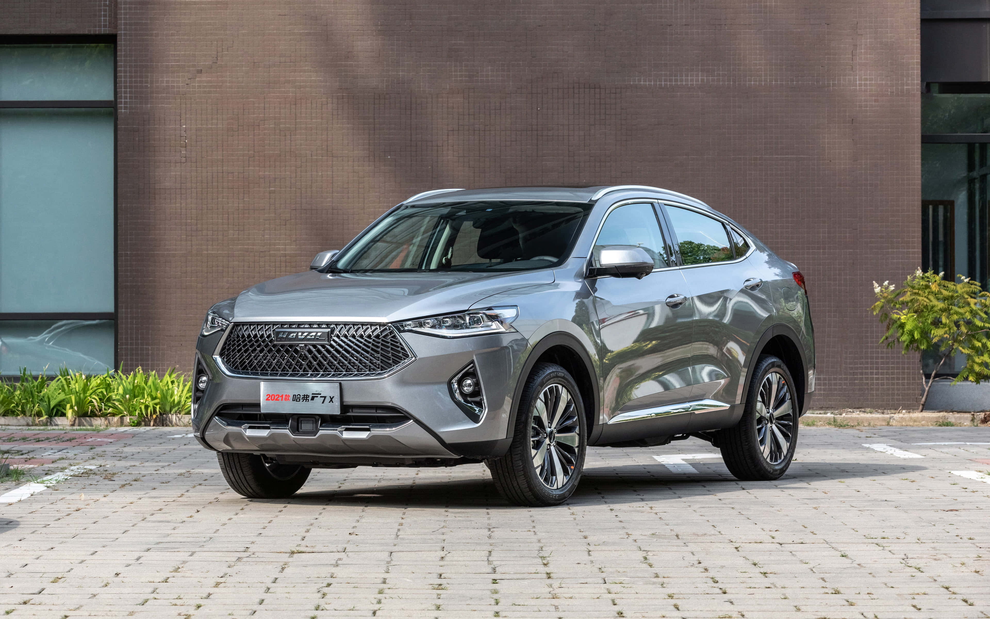 Haval 桌布 壁紙 — 一輛時尚的銀色SUV停放在鋪砌的庭院中，背景是現代磚砌建築和綠植。