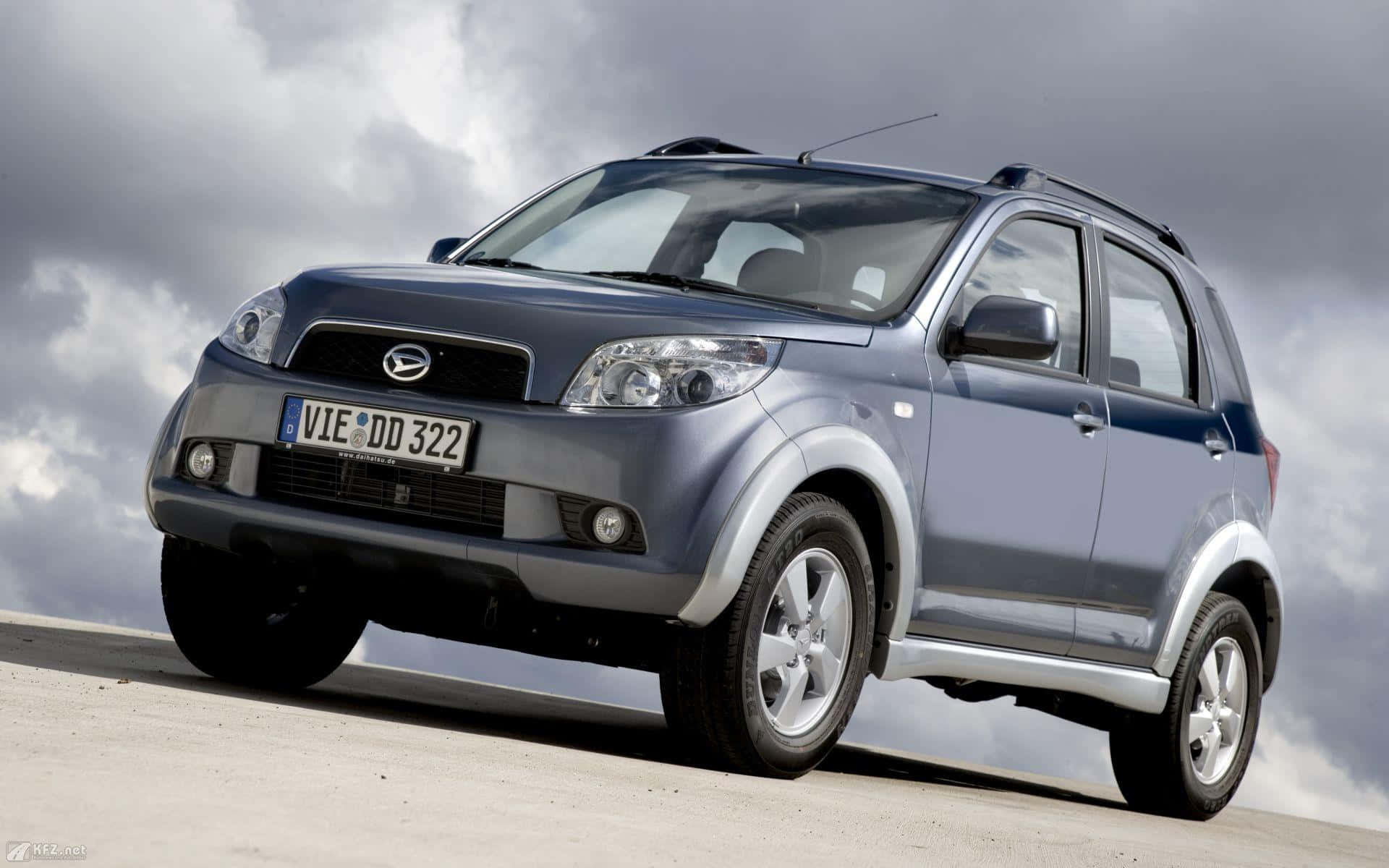 Daihatsu 桌布 壁紙 — 一輛時尚的銀色SUV在戲劇性的多雲天空下停放在混凝土表面上。