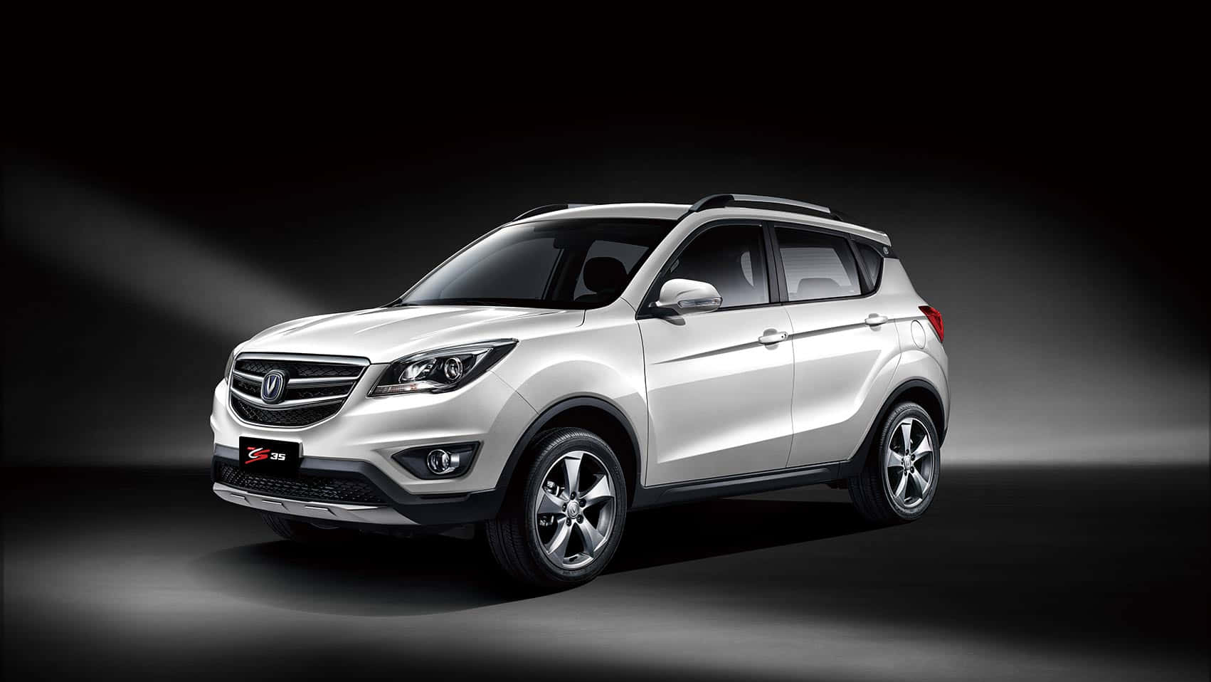 Changan 桌布 壁紙 — 一輛時尚的銀色SUV在黑暗的攝影棚背景下被戲劇性地照亮，聚光燈光束突顯其現代設計。