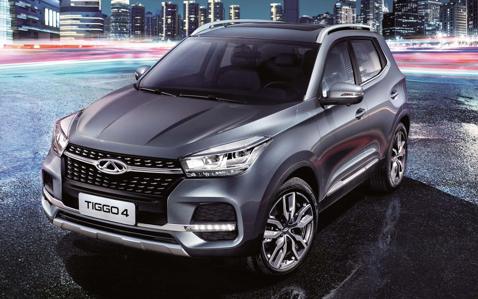 Chery 桌布 壁紙 — 一輛時尚的銀色Tiggo 4 SUV在潮濕的瀝青路上，城市燈光下閃耀，身後有模糊的車流線條。
