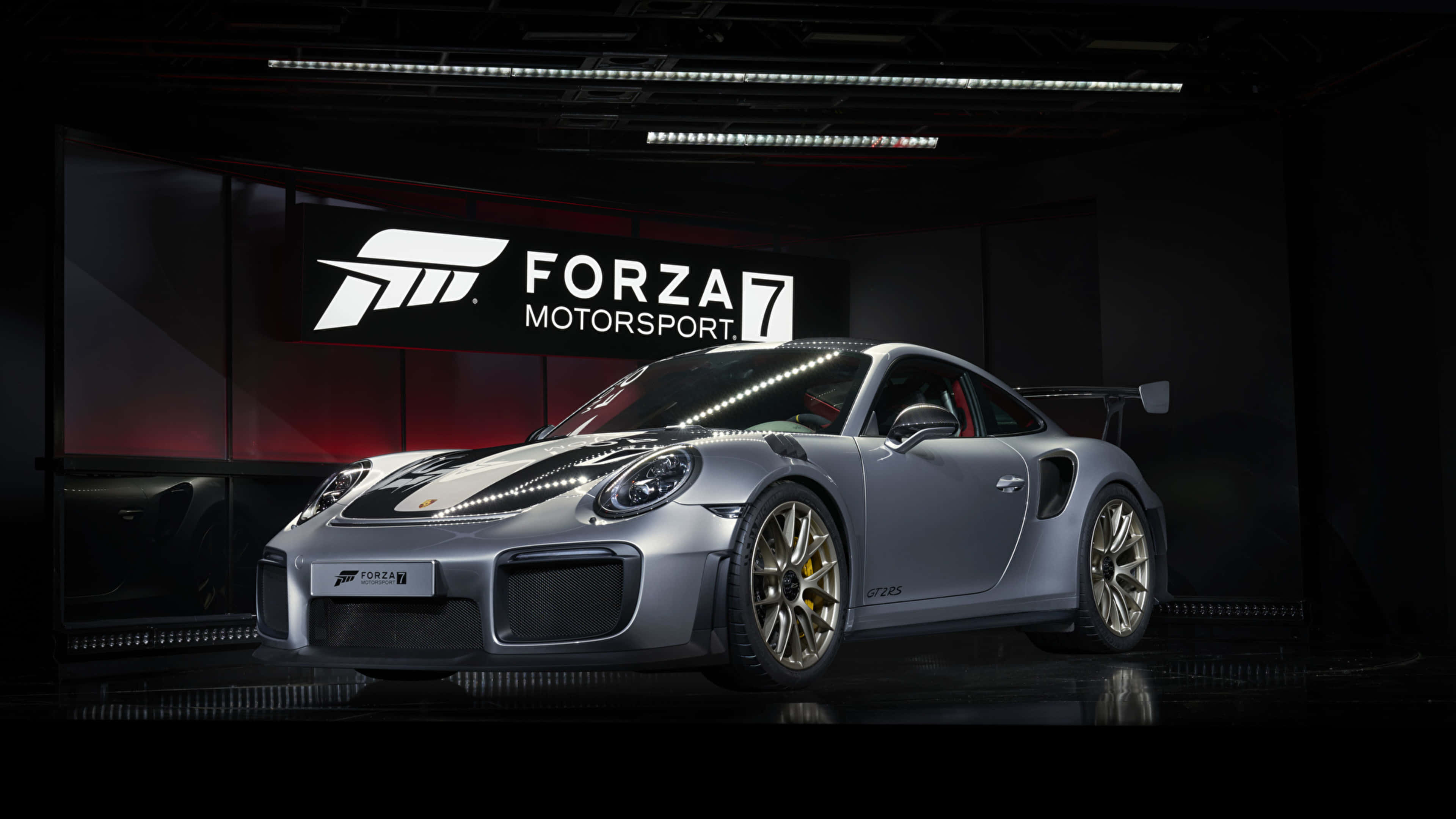 電玩遊戲 桌布 壁紙 — 一輛時尚的銀色保時捷911 GT2 RS配備金色輪圈，在黑暗的Forza Motorsport 7品牌車庫中於工作室燈光下展示。