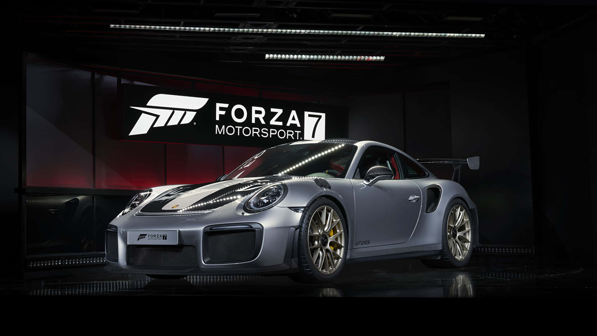 1920x1080 Forza Motorsport 7 桌布 壁紙 — 一輛時尚的銀色保時捷911 GT2 RS配金色輪圈，在工作室燈光下展示，背景為深色並帶有Forza Motorsport 7標誌。