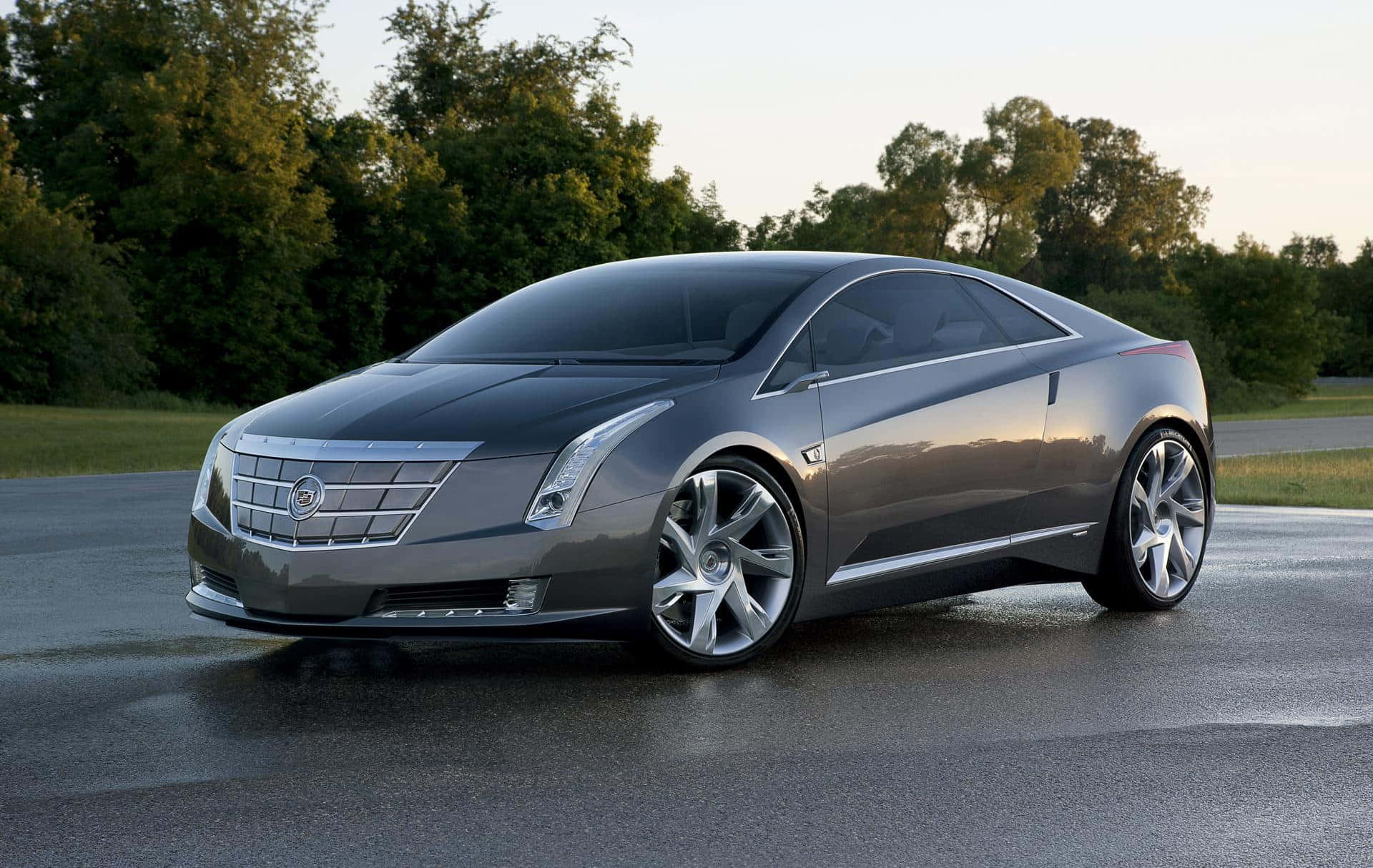 Cadillac Elr 桌布 壁紙 — 一輛時尚的銀色凱迪拉克概念車在黃金時段濕滑的道路上閃耀，背景是茂密的綠樹。