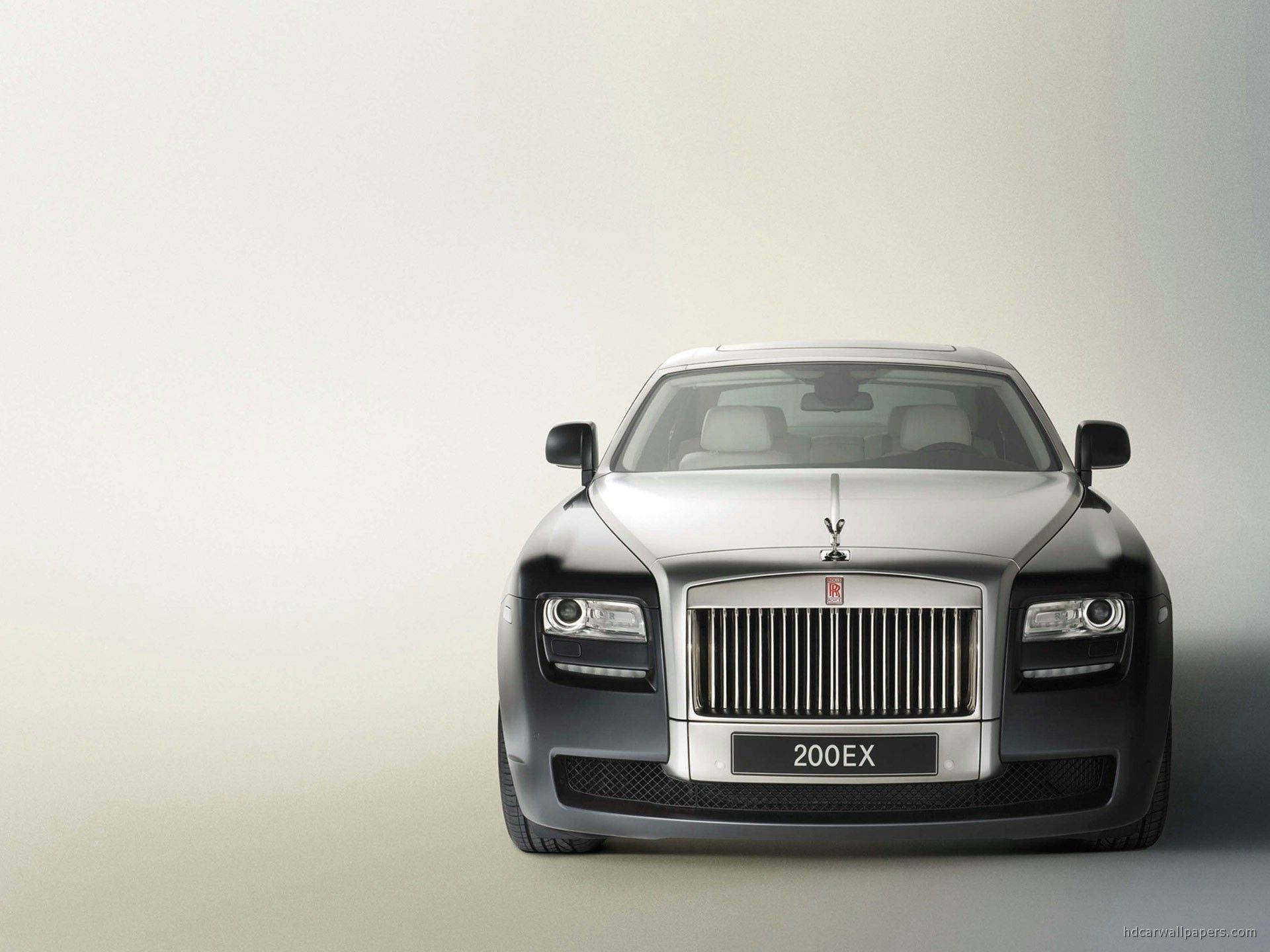 Royce 桌布 壁紙 — 一輛時尚的銀色勞斯萊斯 Ghost 正面朝向極簡工作室背景，光線柔和。